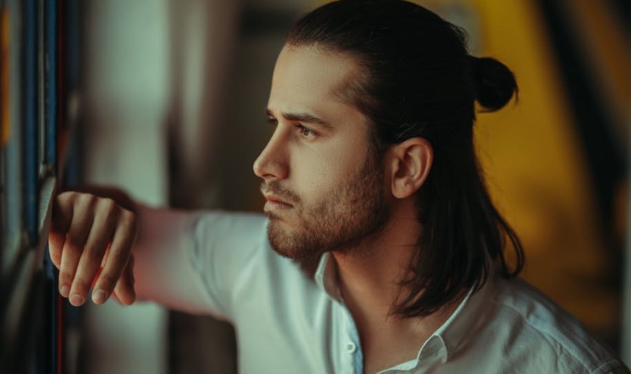 Portrait of a man gazing out a window in Piranshahr, Iran, soft natural light enhancing mood