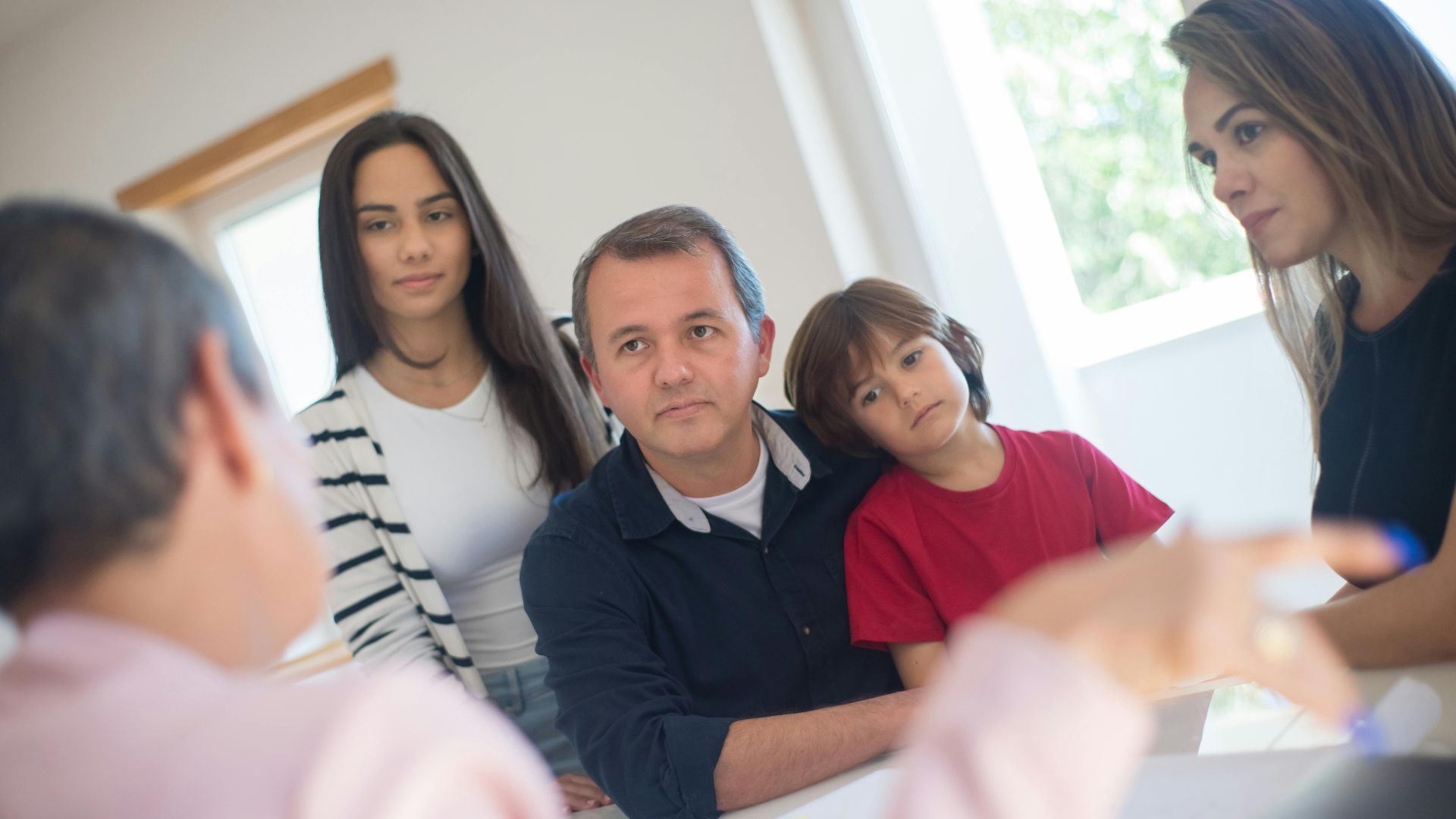 A family of four seeks advice from a professional during an indoor consultation in a bright room.