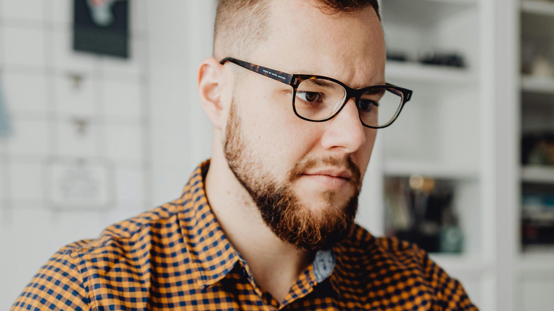 Male professional using a laptop and holding a coffee in a home office setting.