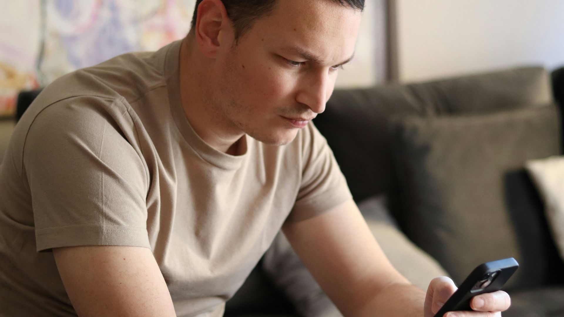 a man sitting on a couch looking at his cell phone