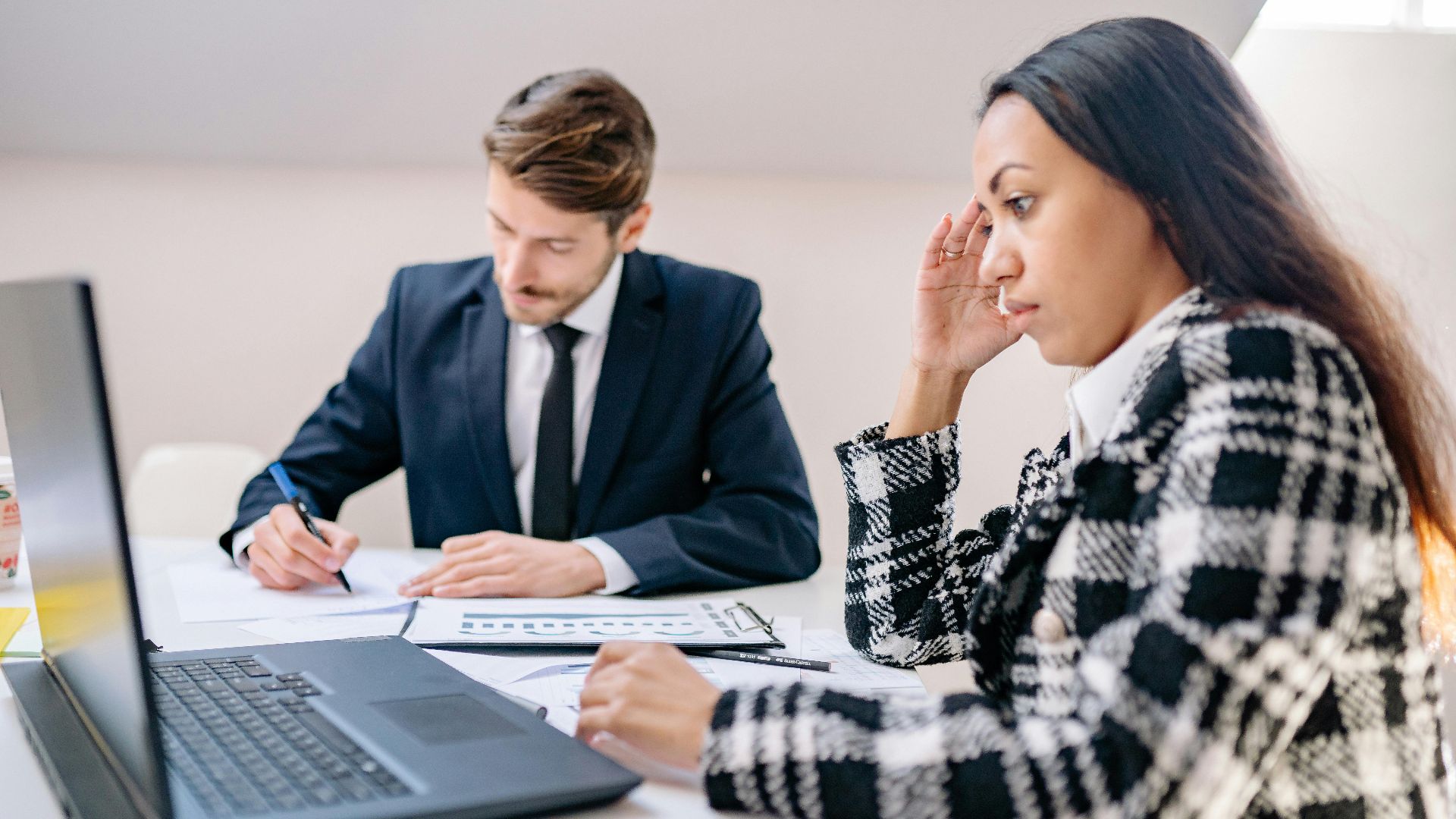 Two business professionals working together in an office, focusing on a project.