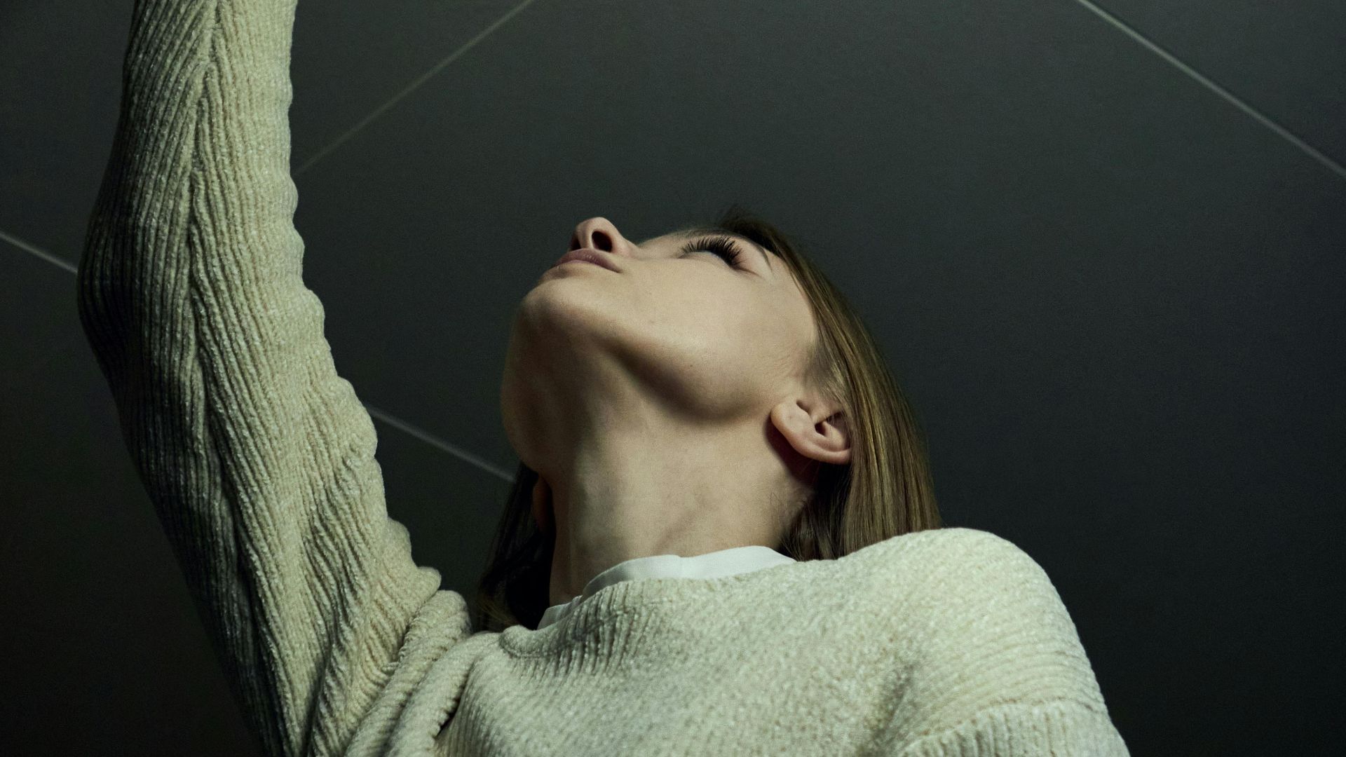 Low angle view of a woman extending her arm towards the ceiling indoors.