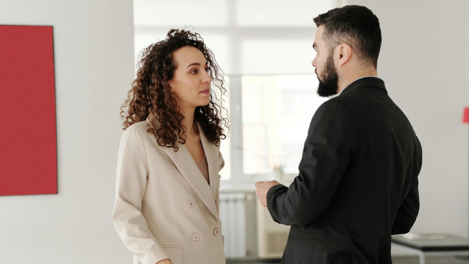 Two professionals engaged in a discussion in a bright, modern office setting.