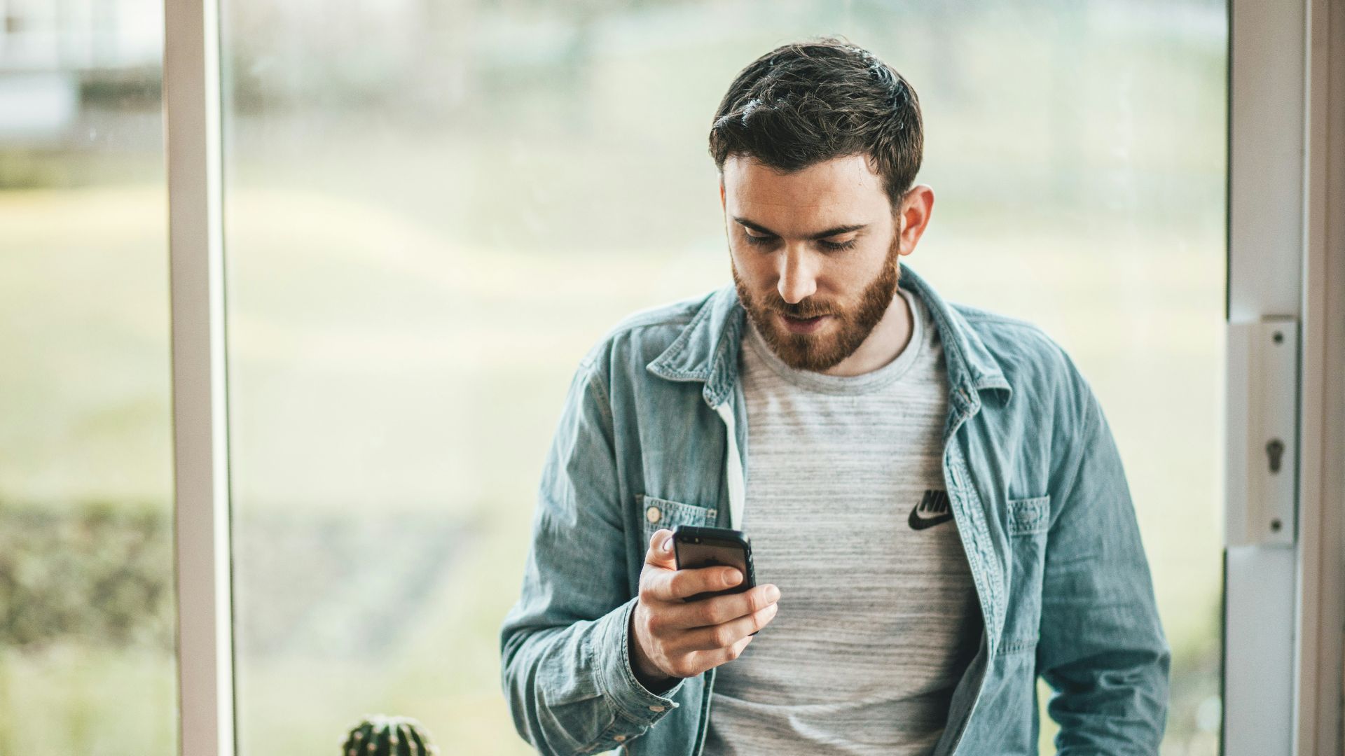 man holding a smartphone near the window