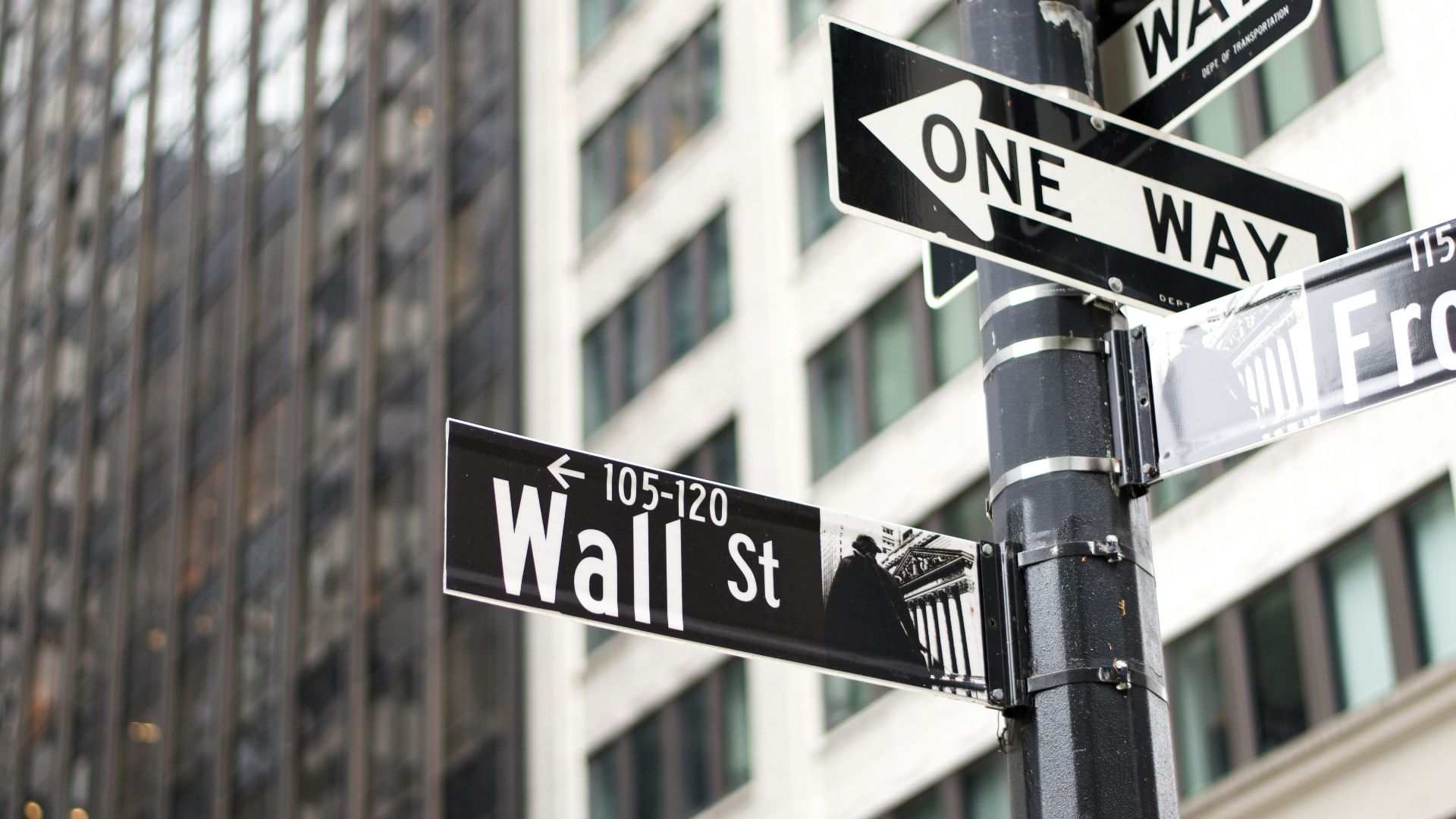 a pole with two street signs and a building in the background