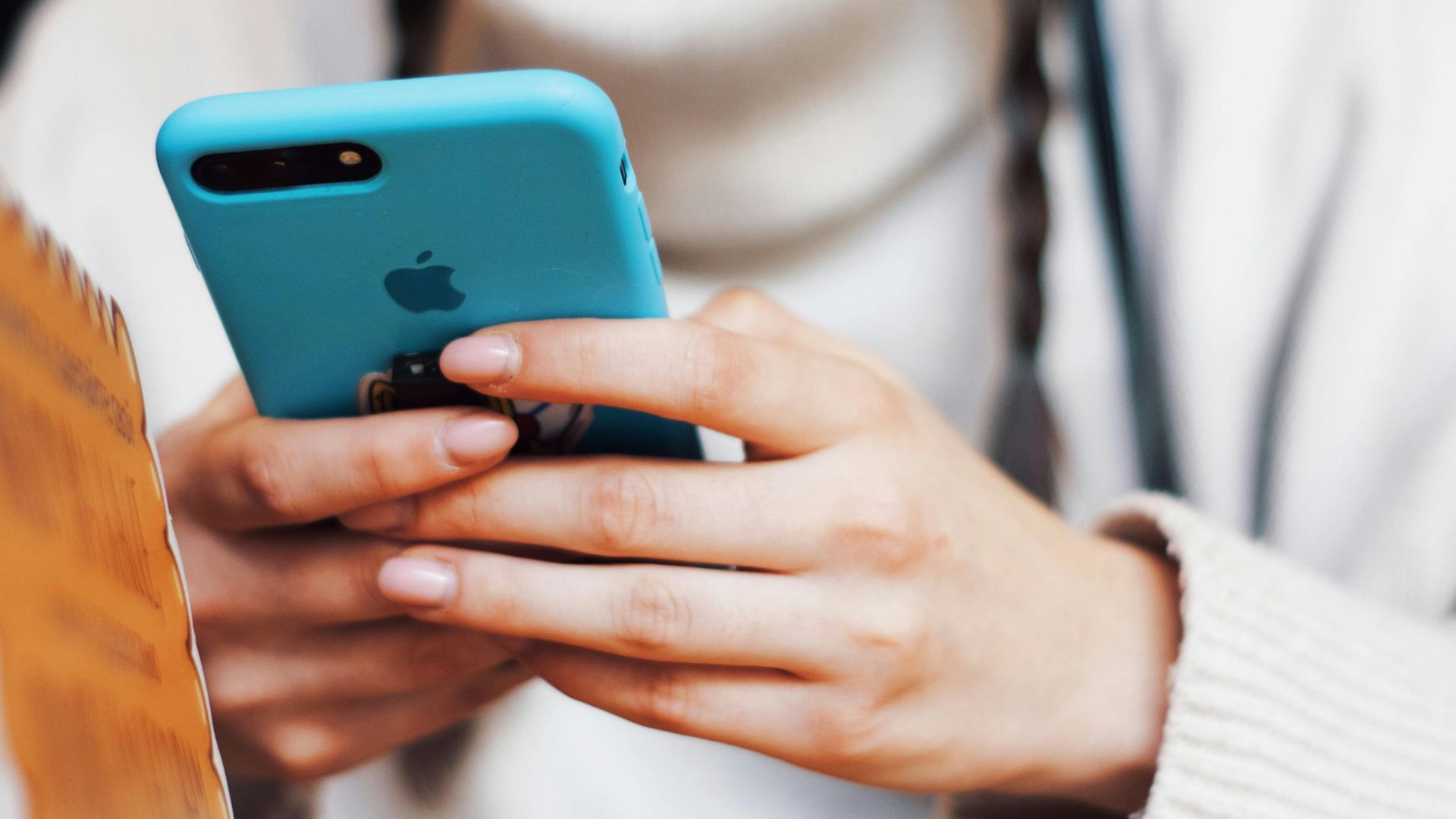 A person texting on a smartphone with a blue case indoors.