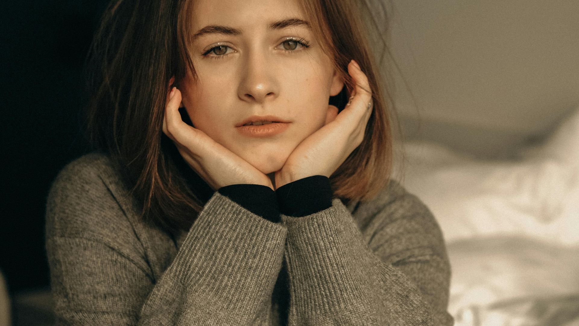 Portrait of a young woman resting on a bed, capturing a serene and contemplative moment indoors.