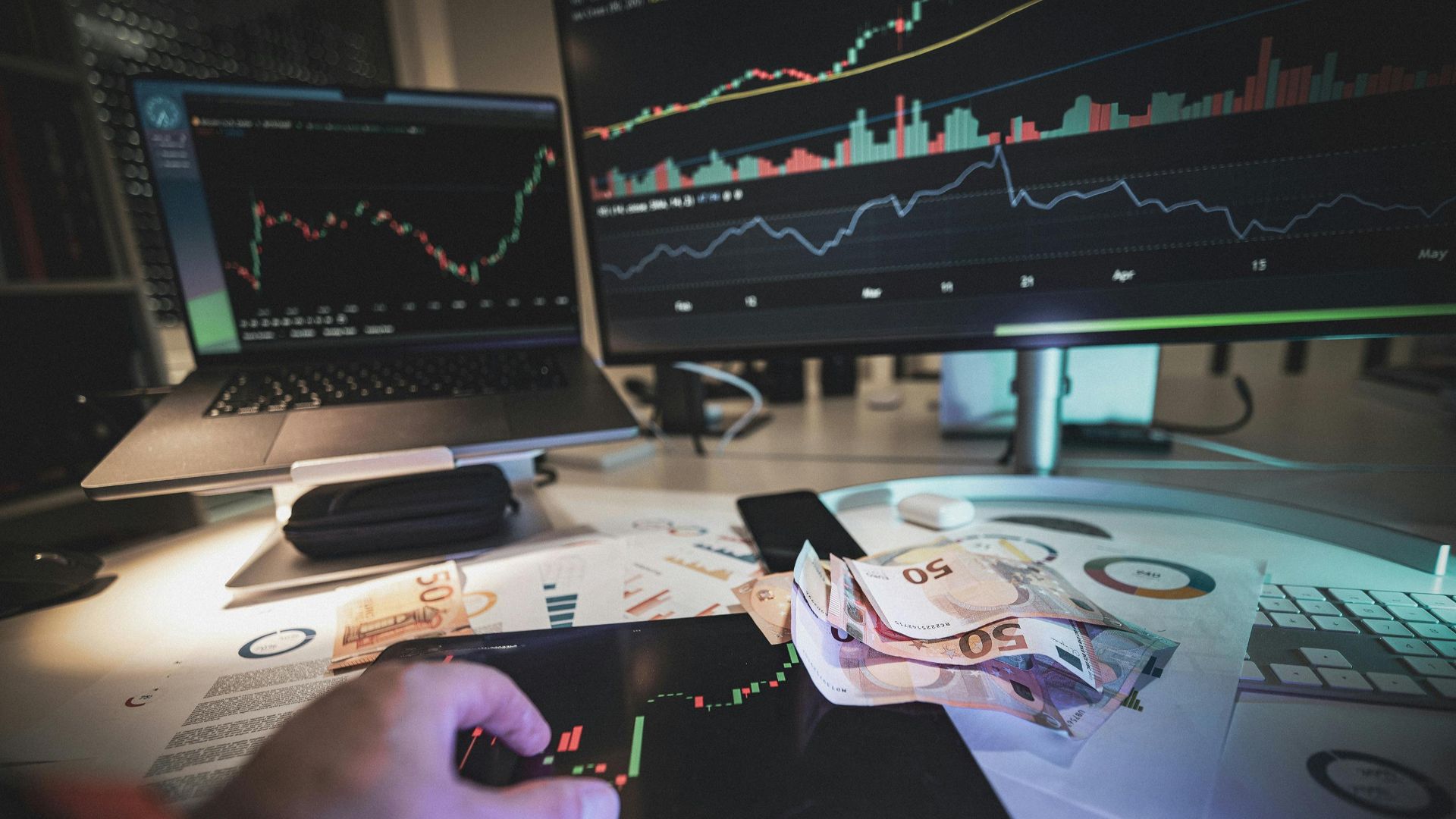 A modern trading desk with screens showing market charts and euro notes, capturing a trading atmosphere.