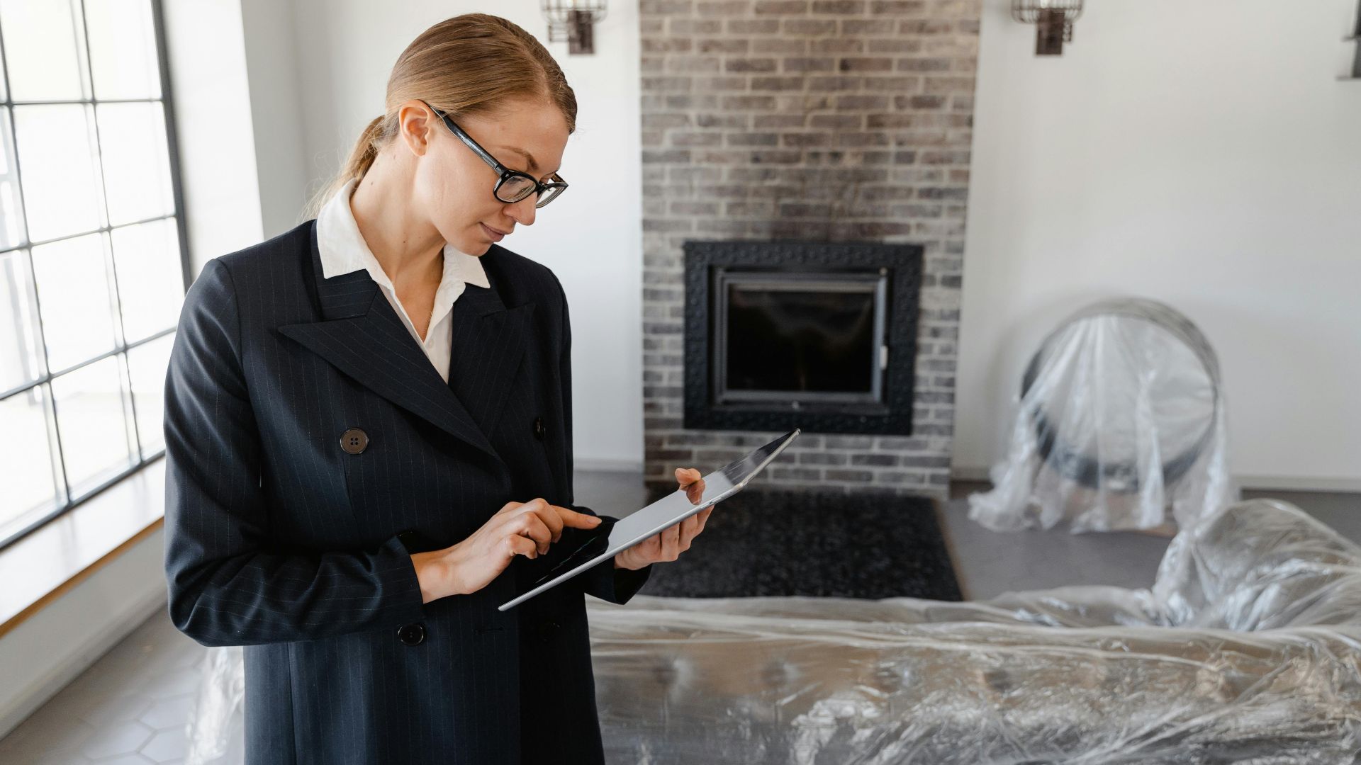 A real estate agent in a suit uses a digital tablet to review documents in a modern living room.