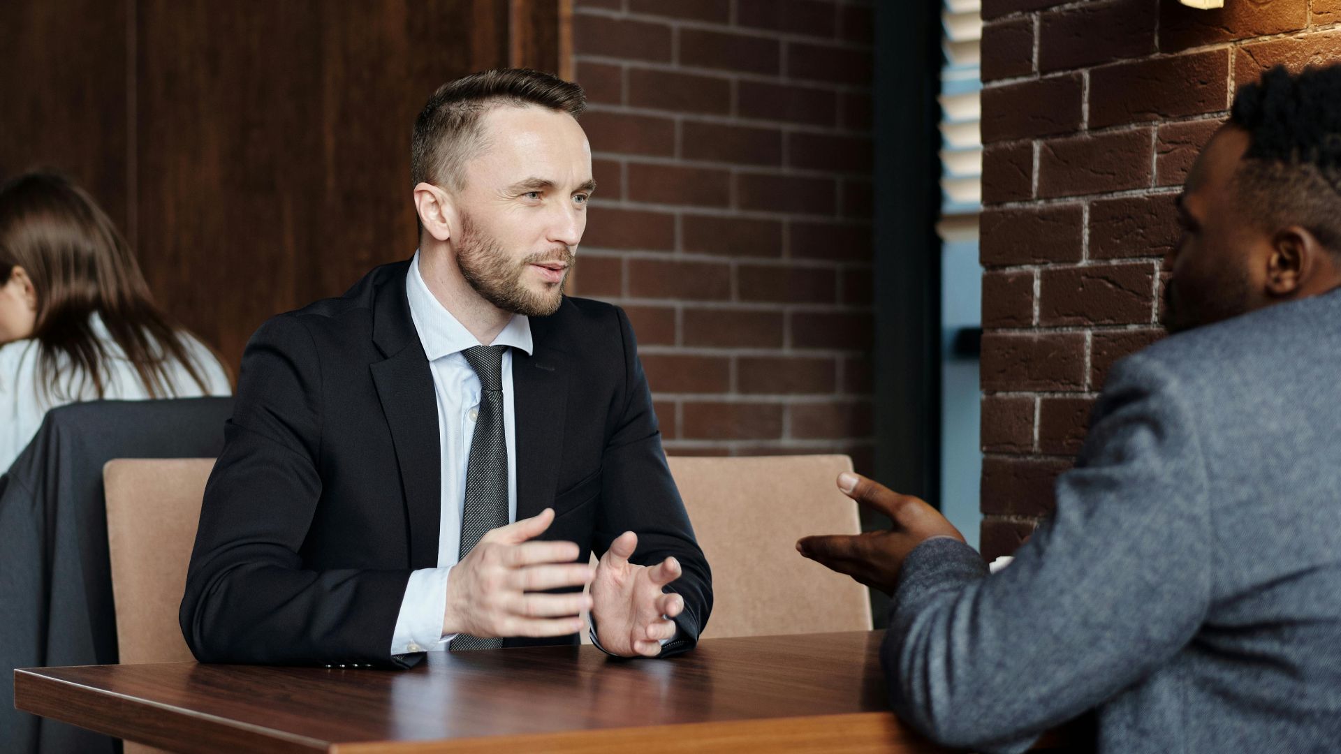 Businessmen engaged in a professional conversation in a stylish café setting.