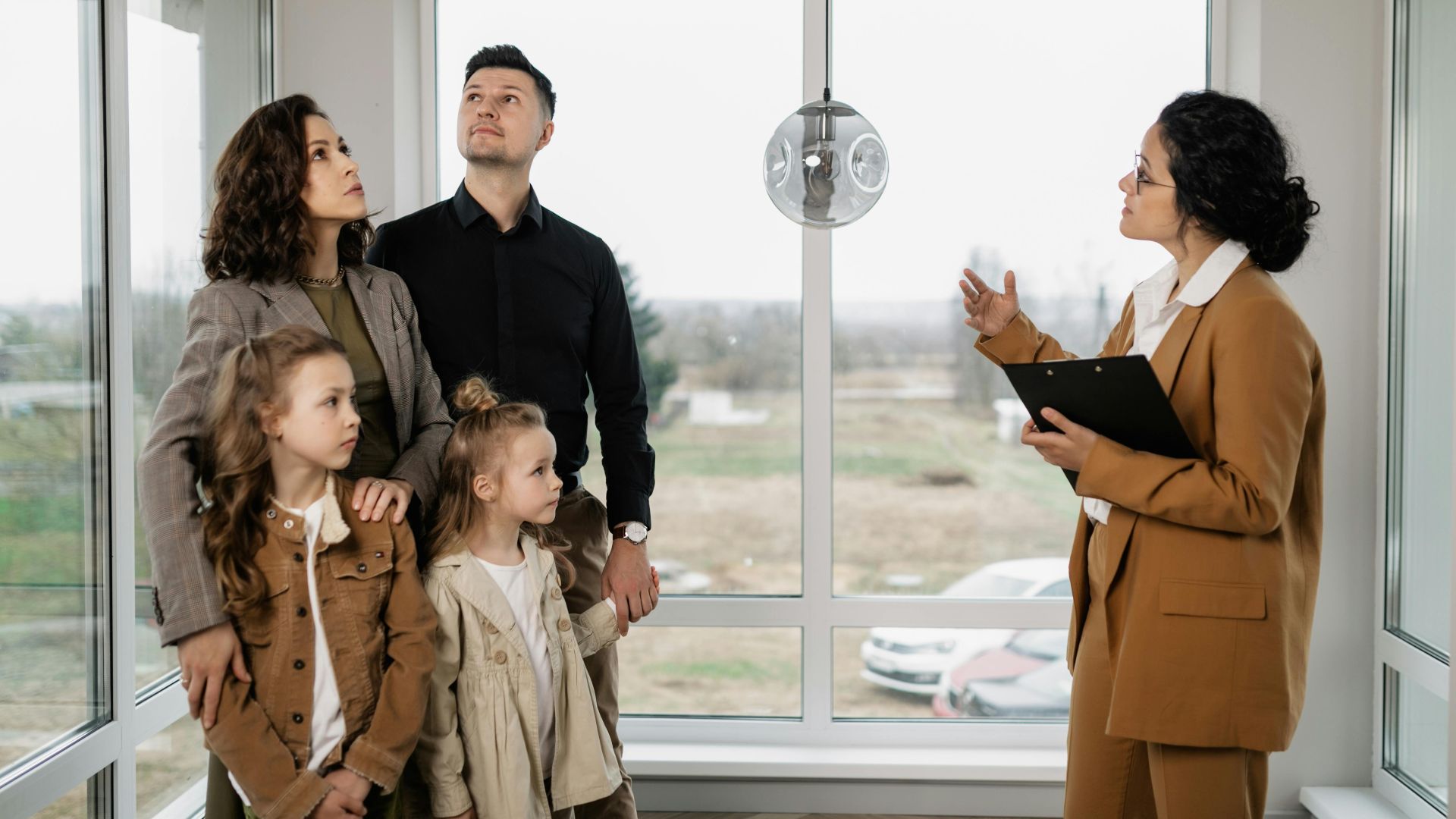 Family with children visits potential new home with a realtor inside modern house.