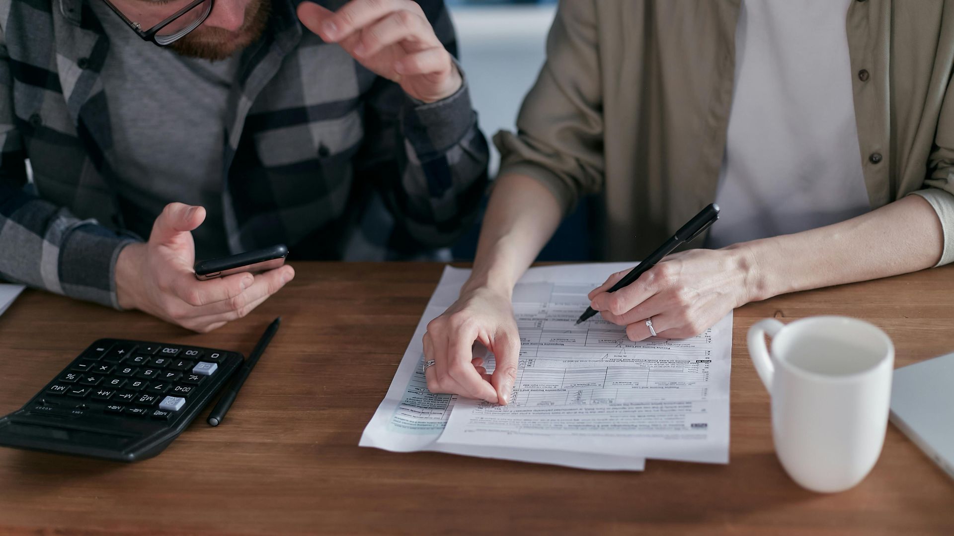 A couple collaboratively managing finances with papers and calculator in hand.