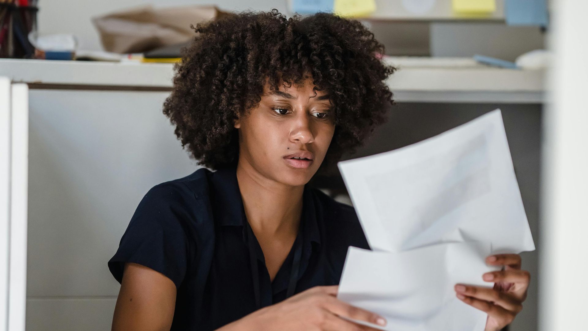 An African American businesswoman reviewing documents on the office floor.