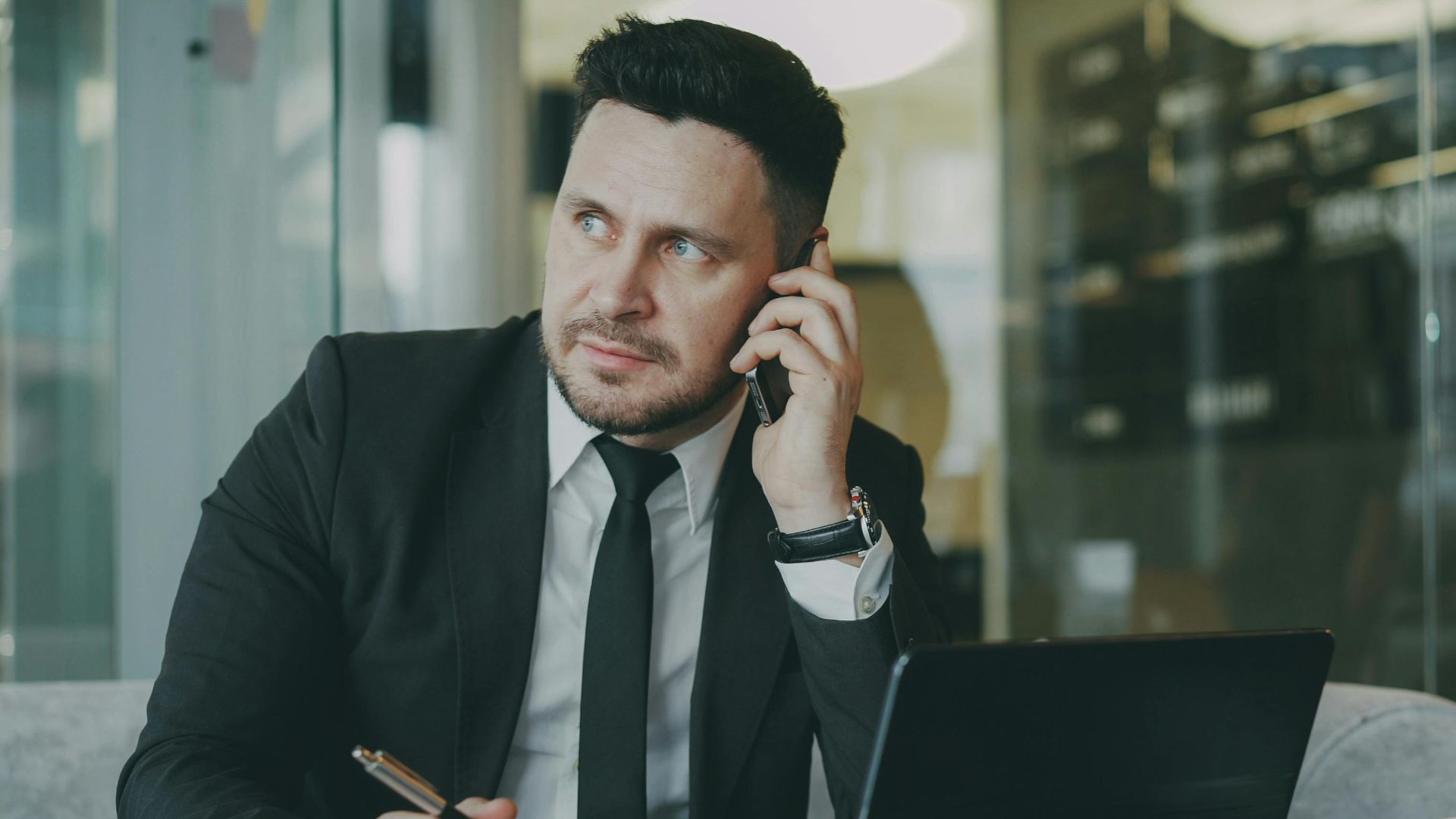 Focused businessman speaking on phone at office desk.