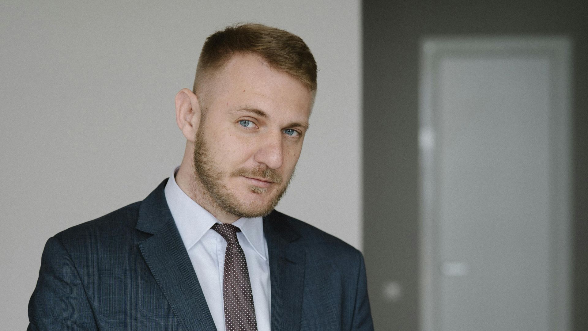 Young businessman in a suit using a laptop indoors, embodying corporate professionalism.