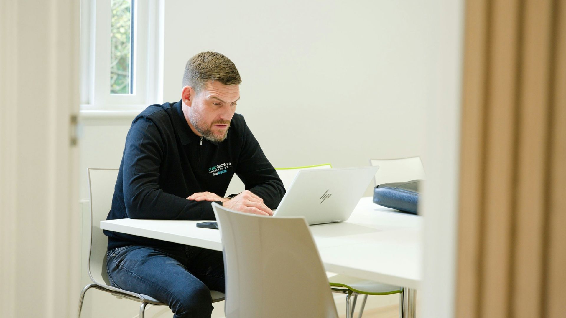 Man working on laptop at a white table.