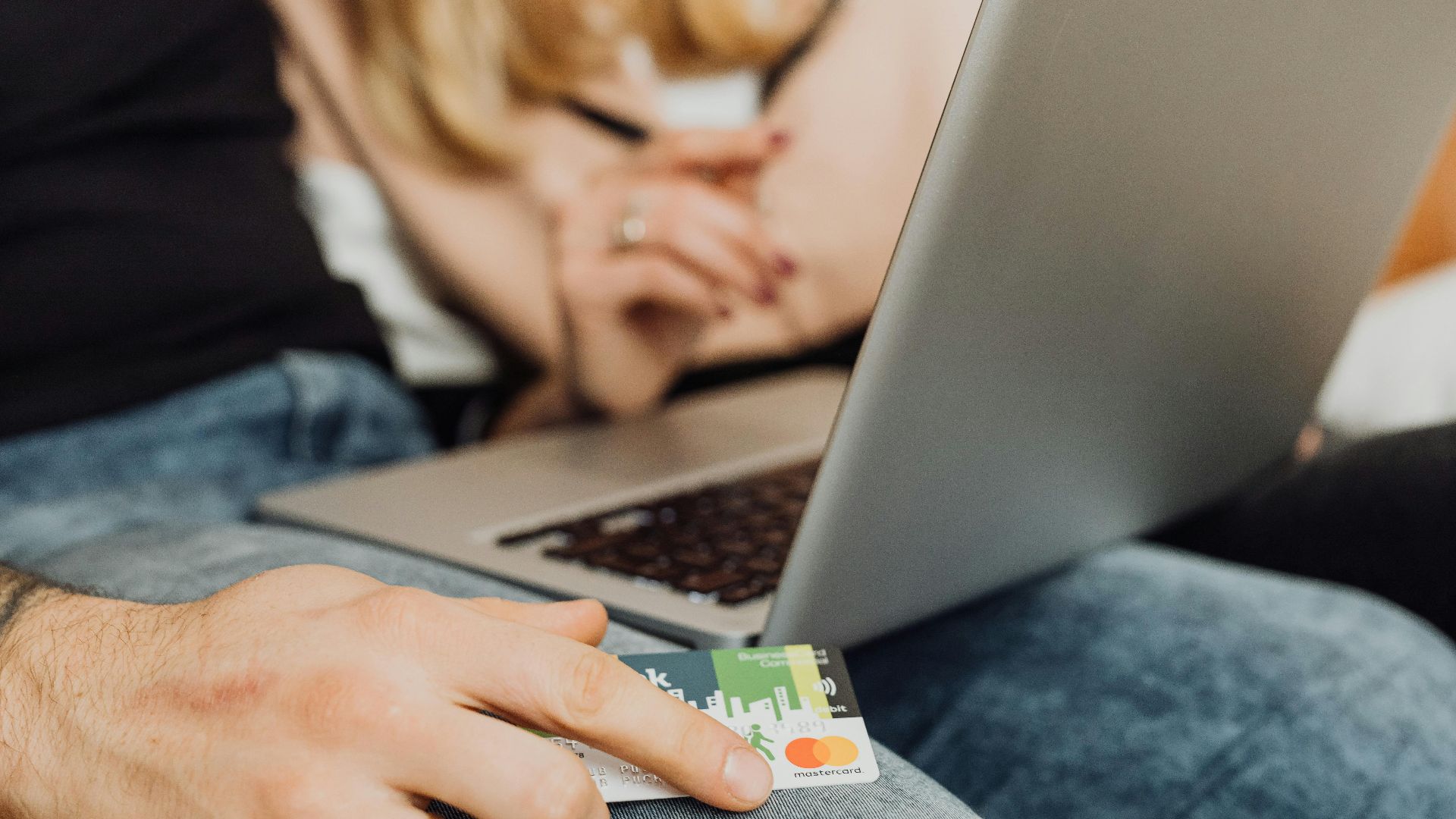 A couple using a laptop for online shopping, holding a credit card in a cozy setting.