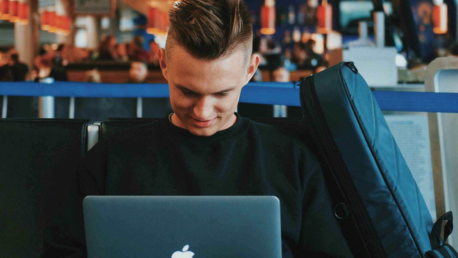 smiling man facing Apple MacBook