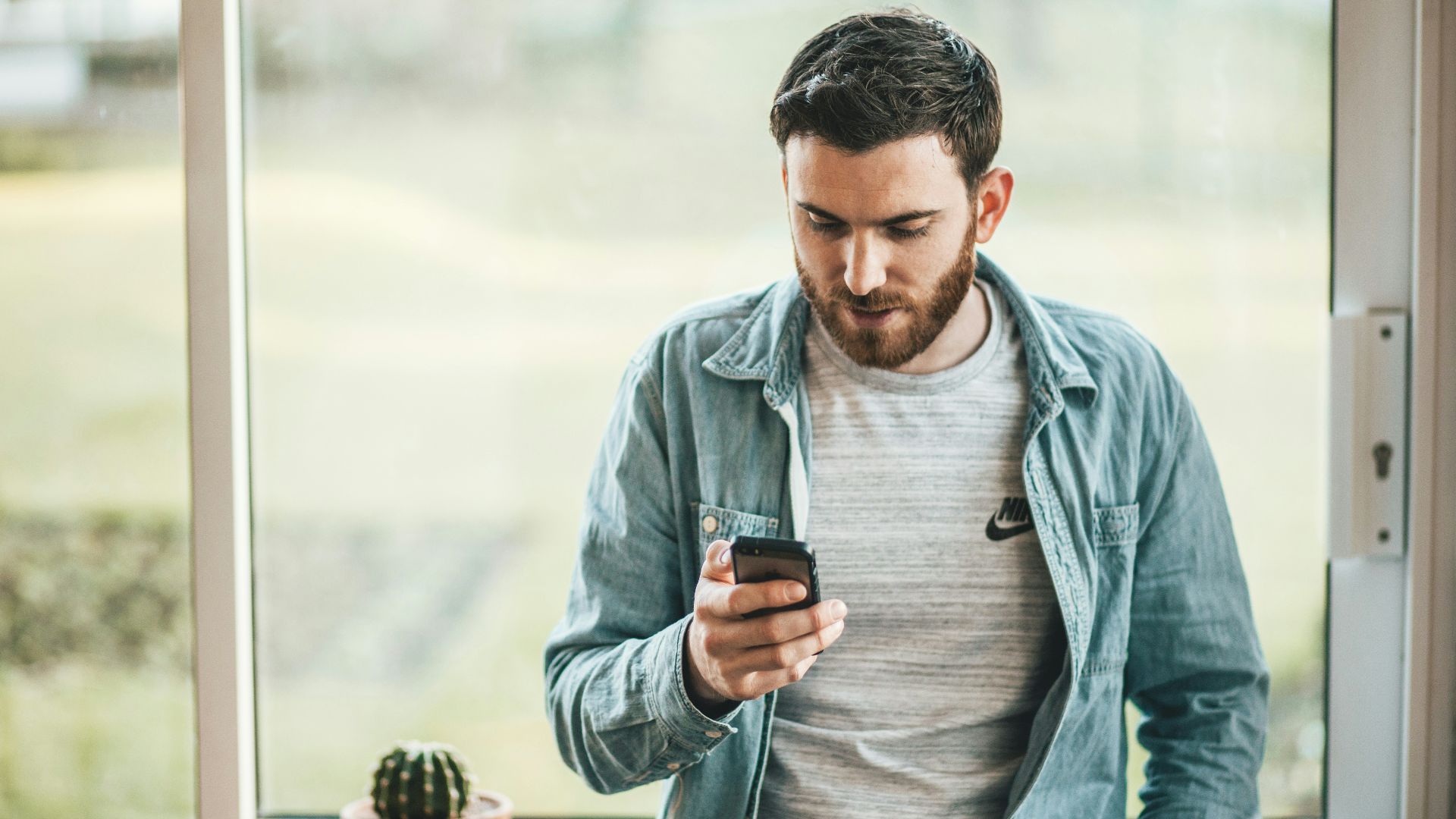 man holding a smartphone near the window