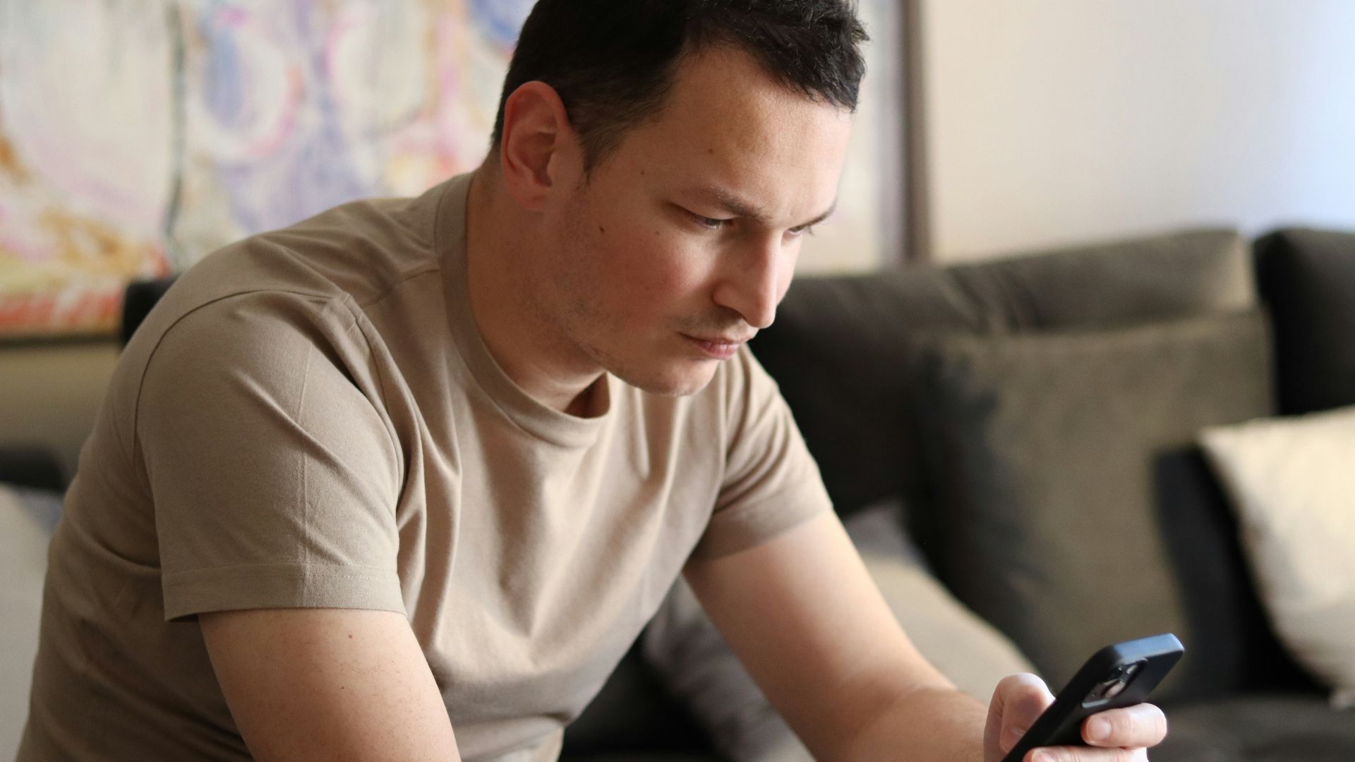 a man sitting on a couch looking at his cell phone