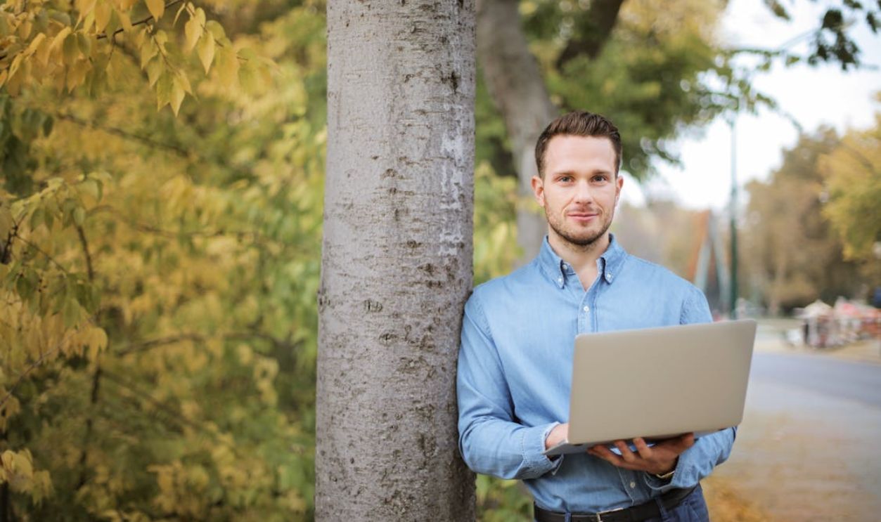 Man using laptop outdoors in a park setting, embracing digital nomad lifestyle
