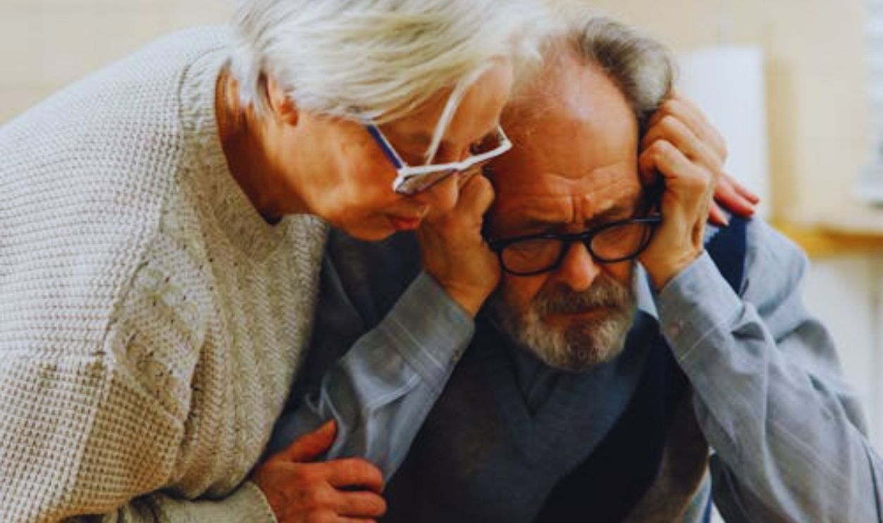 A worried senior couple reviews important documents at their kitchen table