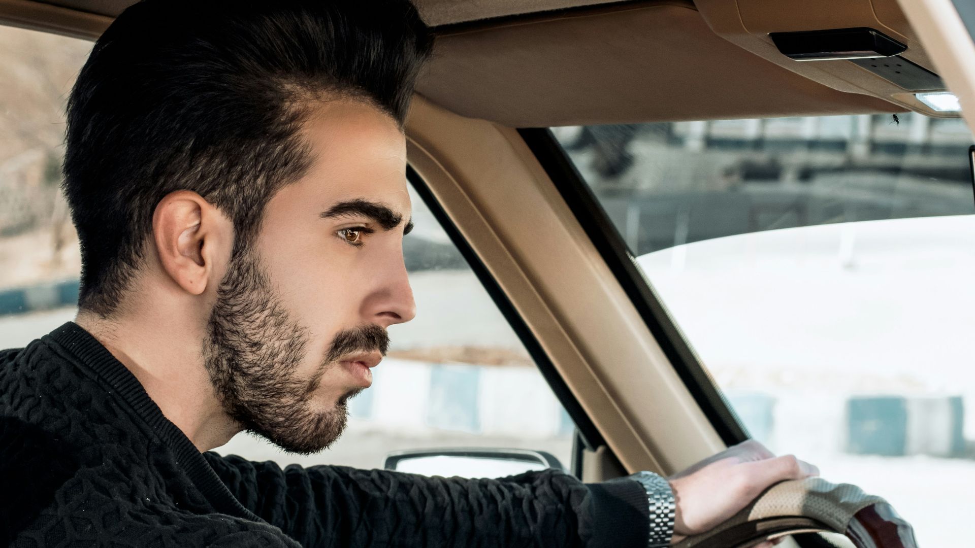 man in black and gray striped long sleeve shirt driving car during daytime