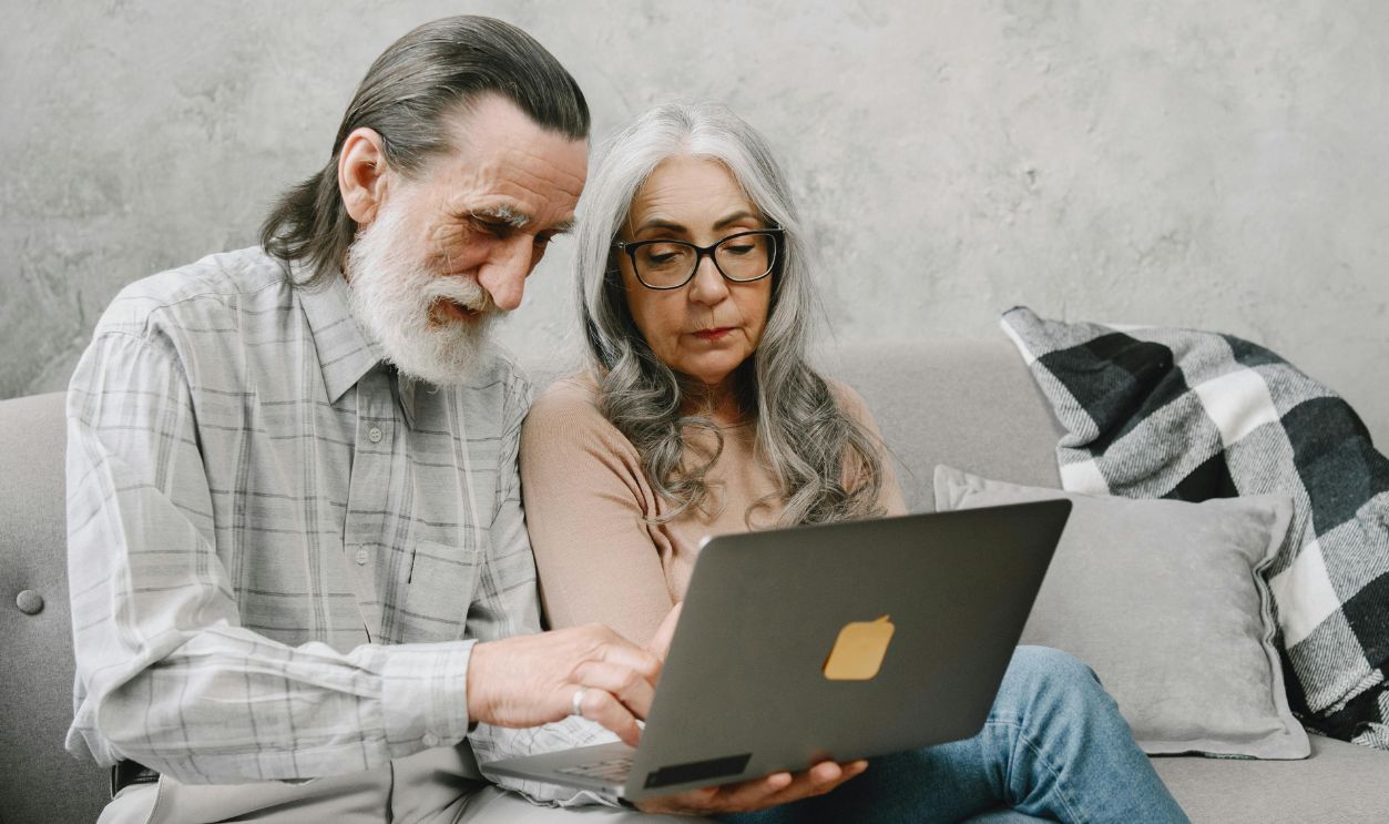 Elderly couple sitting on a couch using a laptop