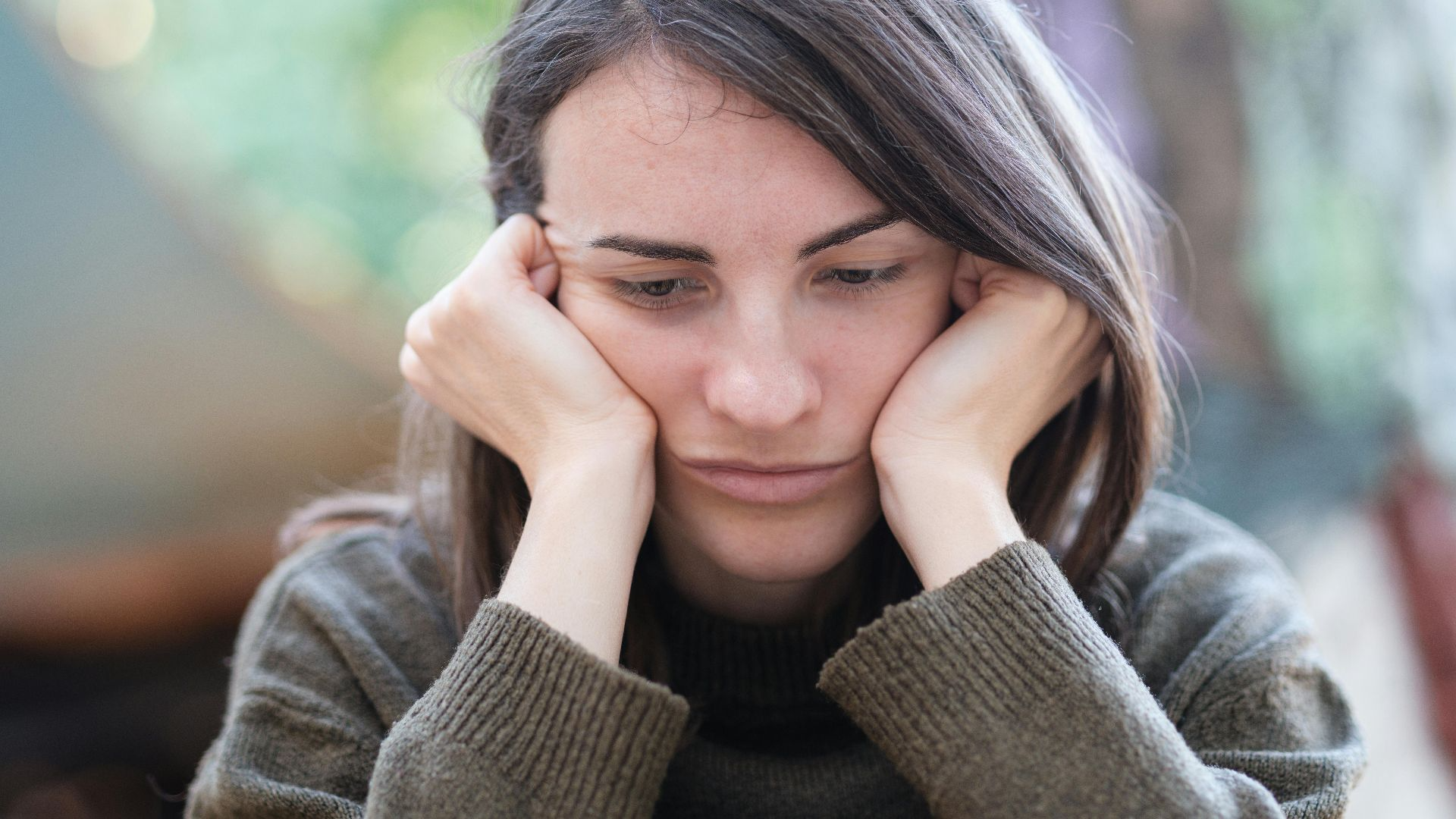 Portrait of a young woman looking pensive and thoughtful while sitting outdoors