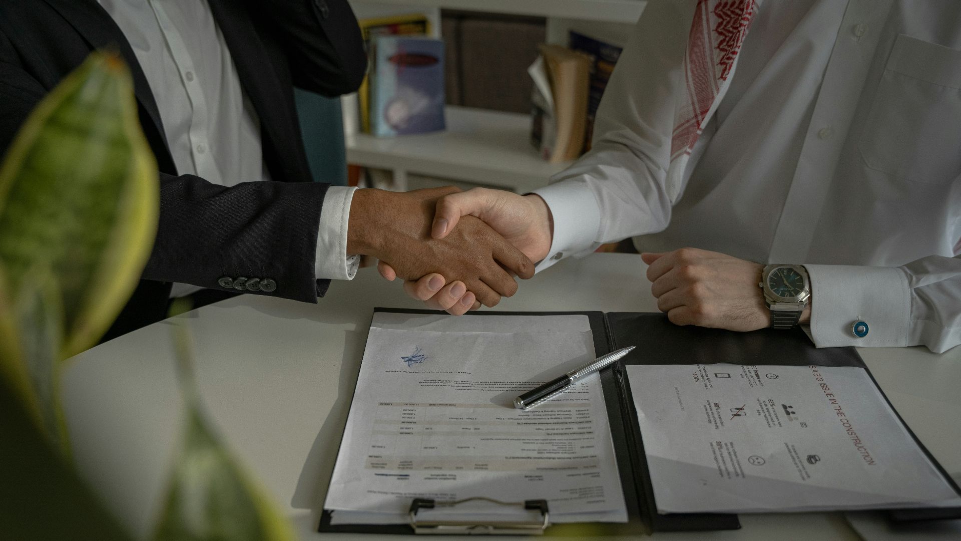 two people shaking hands over a piece of paper