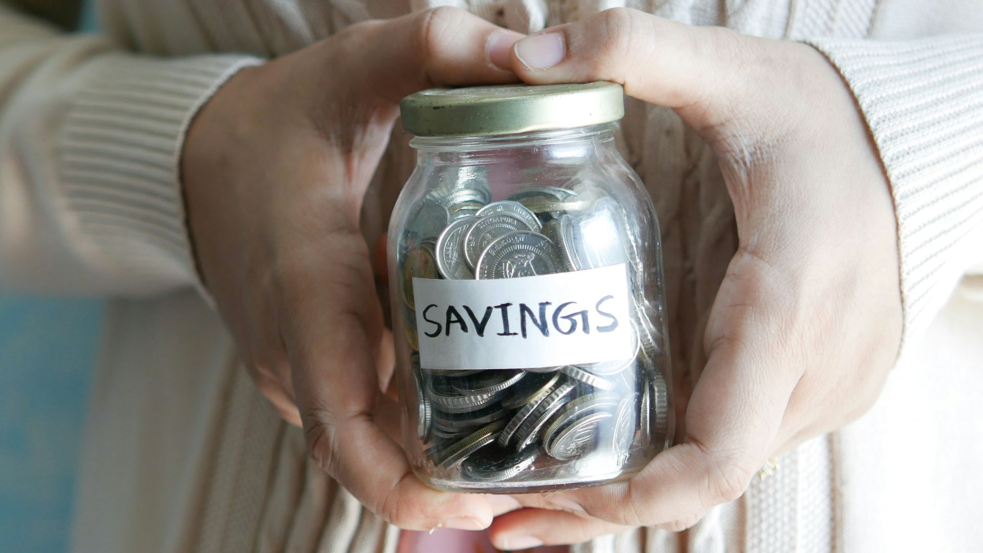 a woman holding a jar with savings written on it