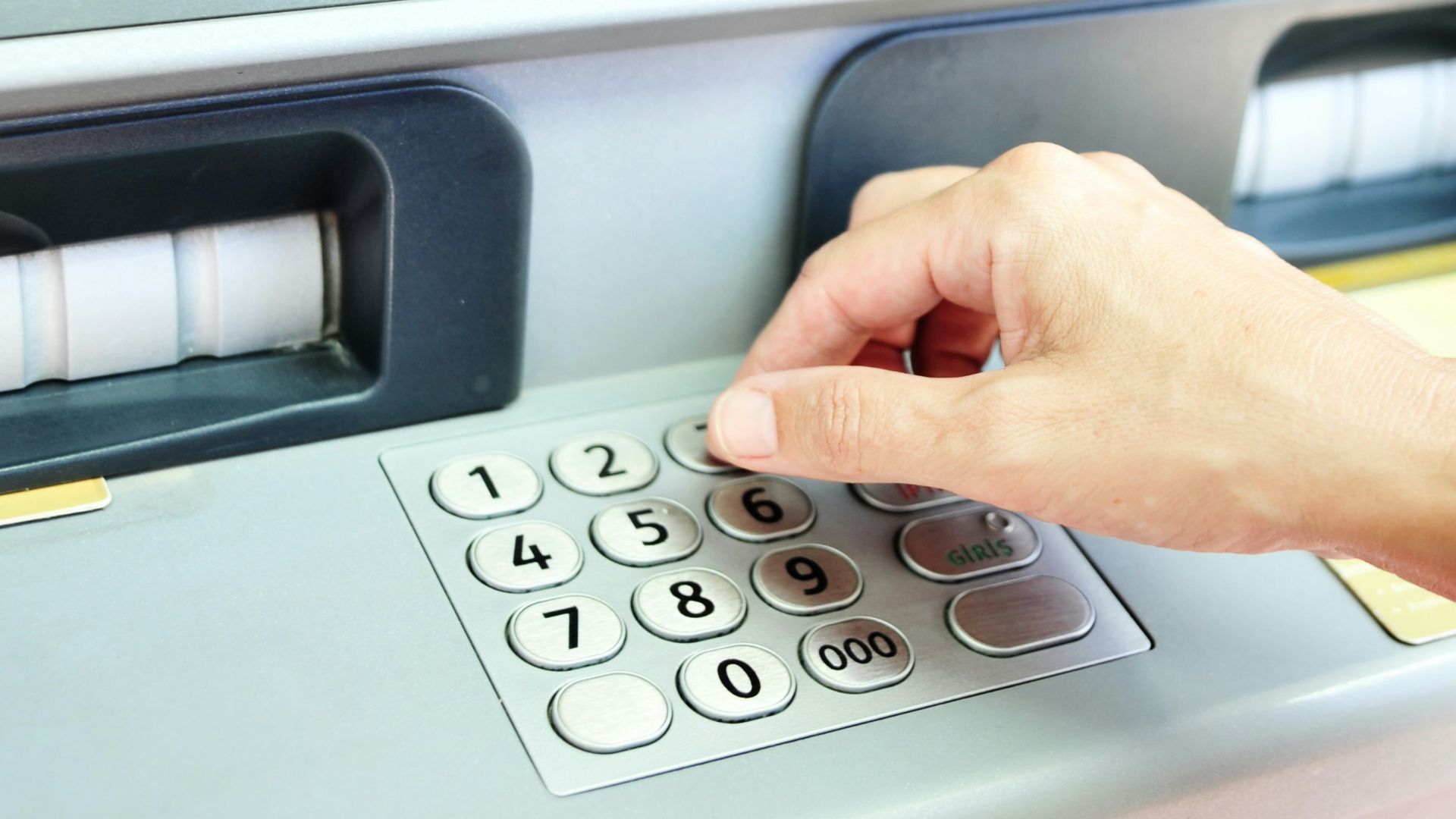 Hand using keypad on an atm machine.