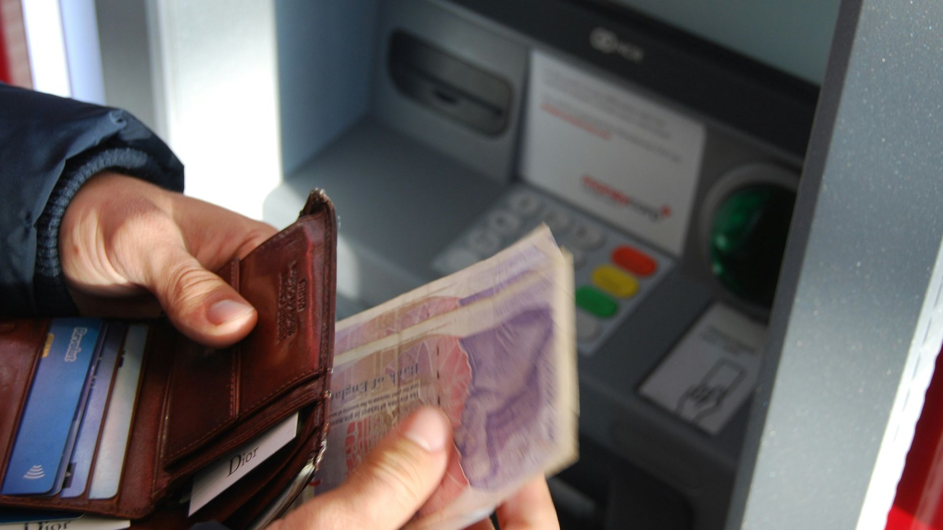 person holding brown leather wallet and banknotes