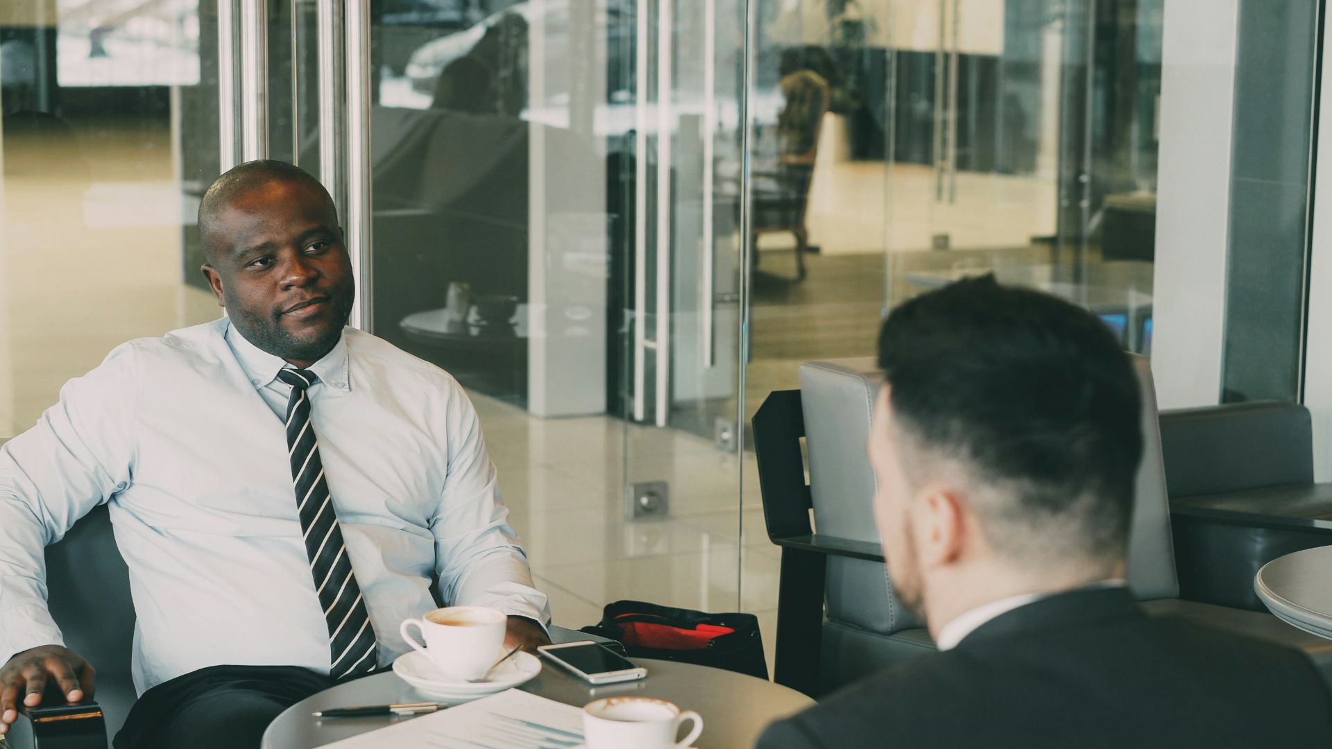 Two businessmen talking at a cafe table.