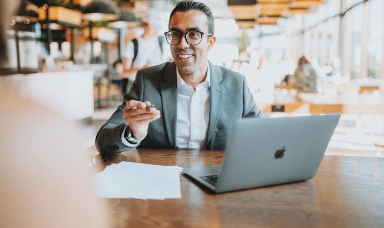 Professional man in suit using laptop in a modern cafe setting. Ideal for business themes