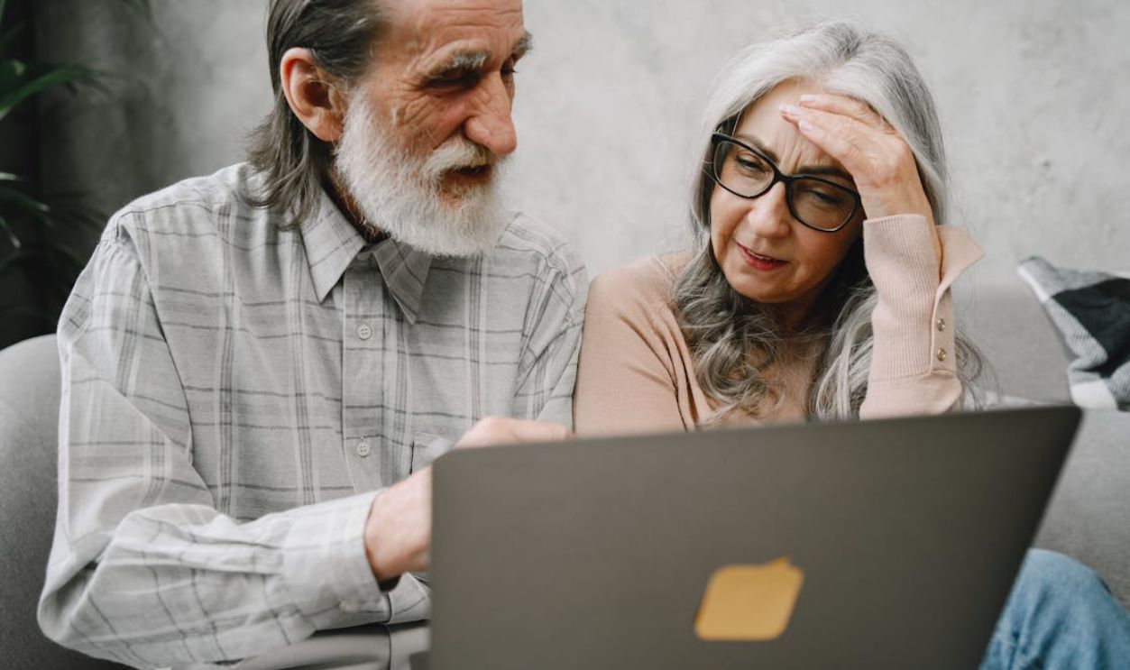 Senior couple using a laptop together at home, engaging in a focused conversation
