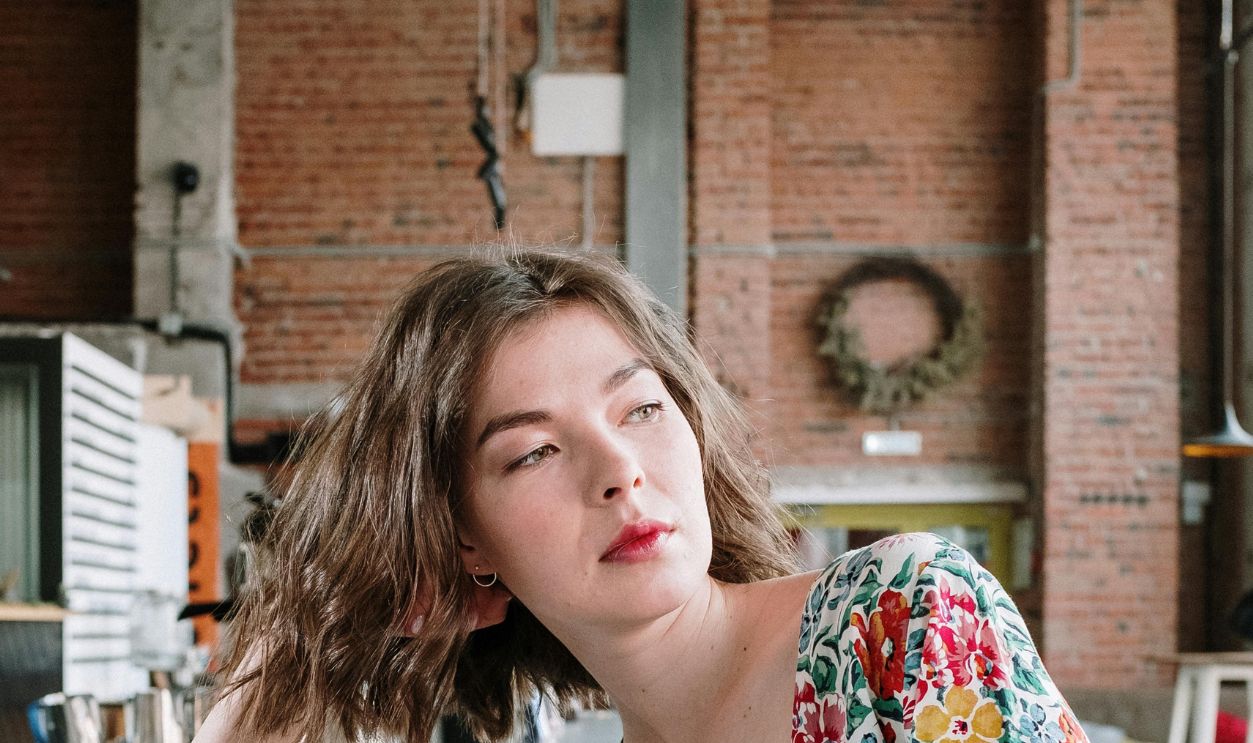 Young woman in a floral dress with laptop working at a stylish loft cafe