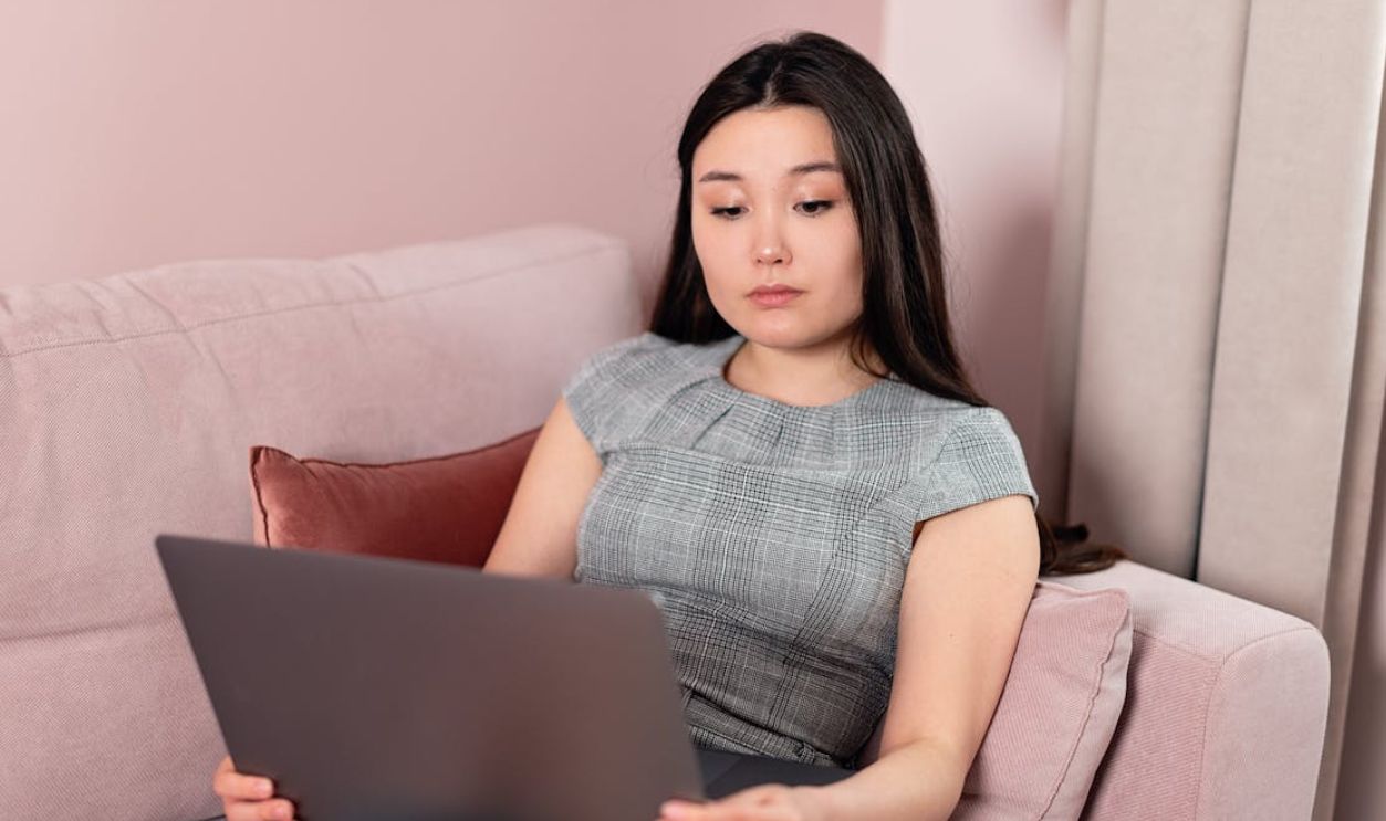 A young woman working on a laptop while sitting on a modern sofa indoors