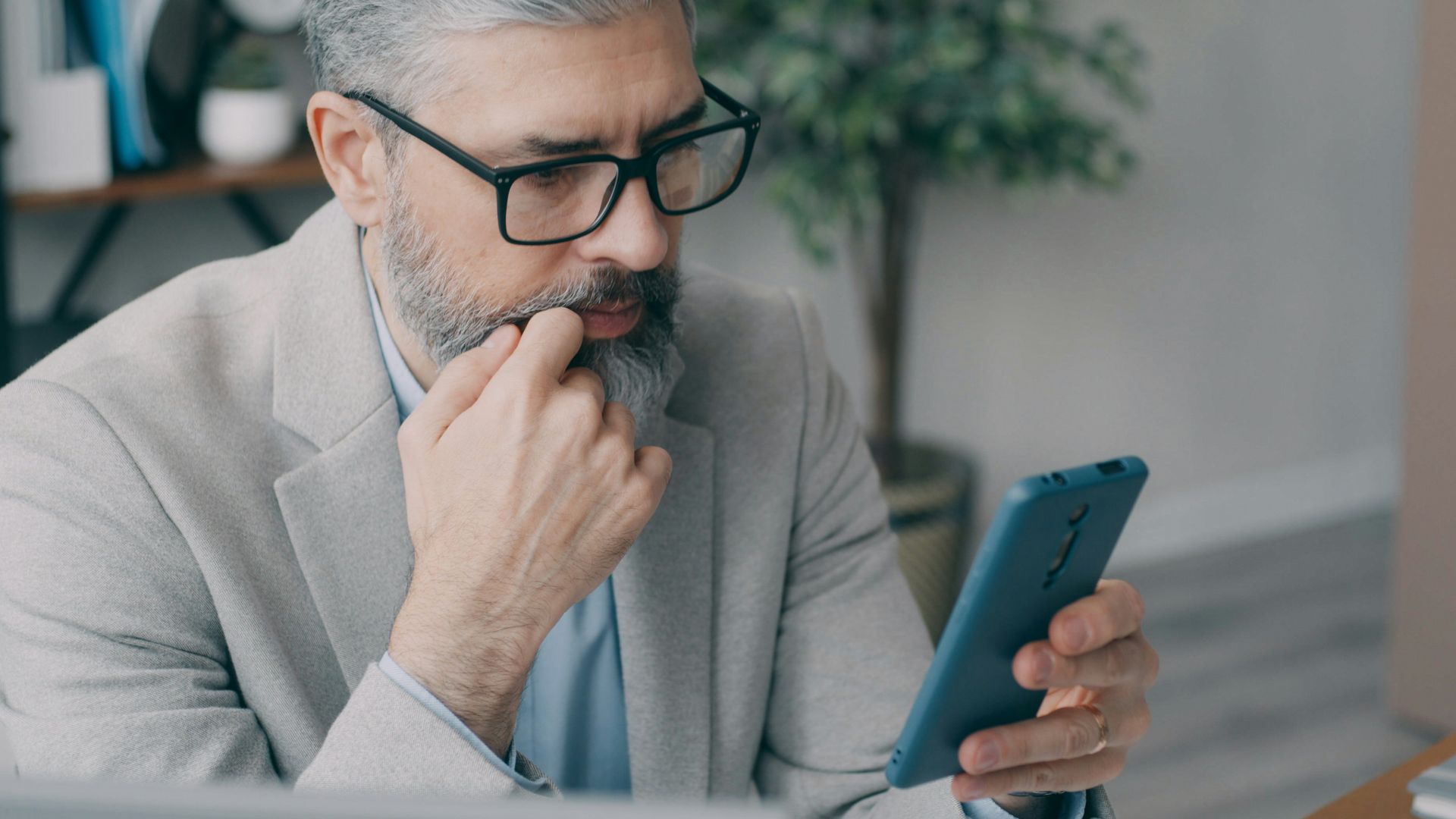 A man sitting at a desk looking at a cell phone