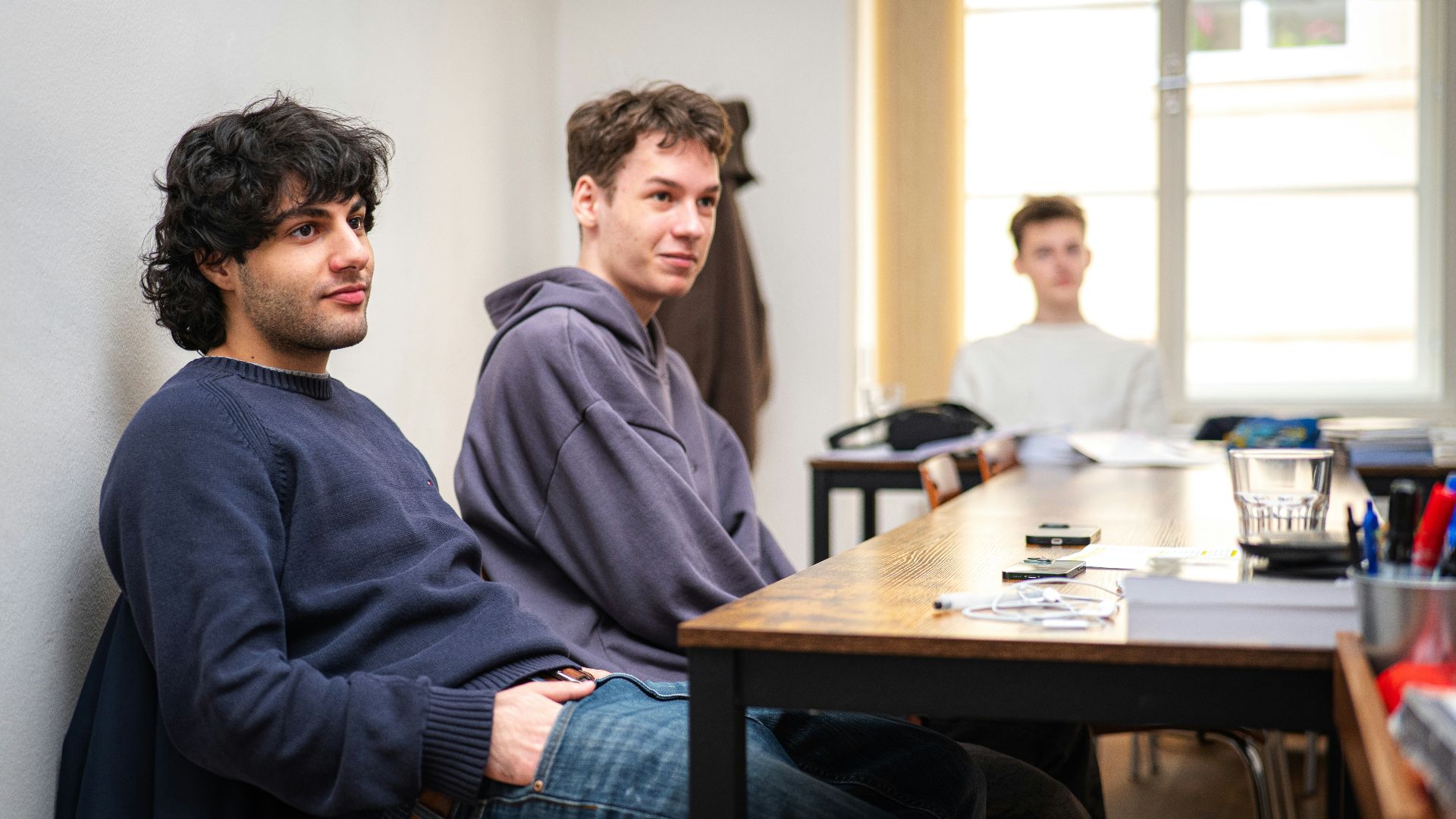 Three young men sitting at a table indoors.