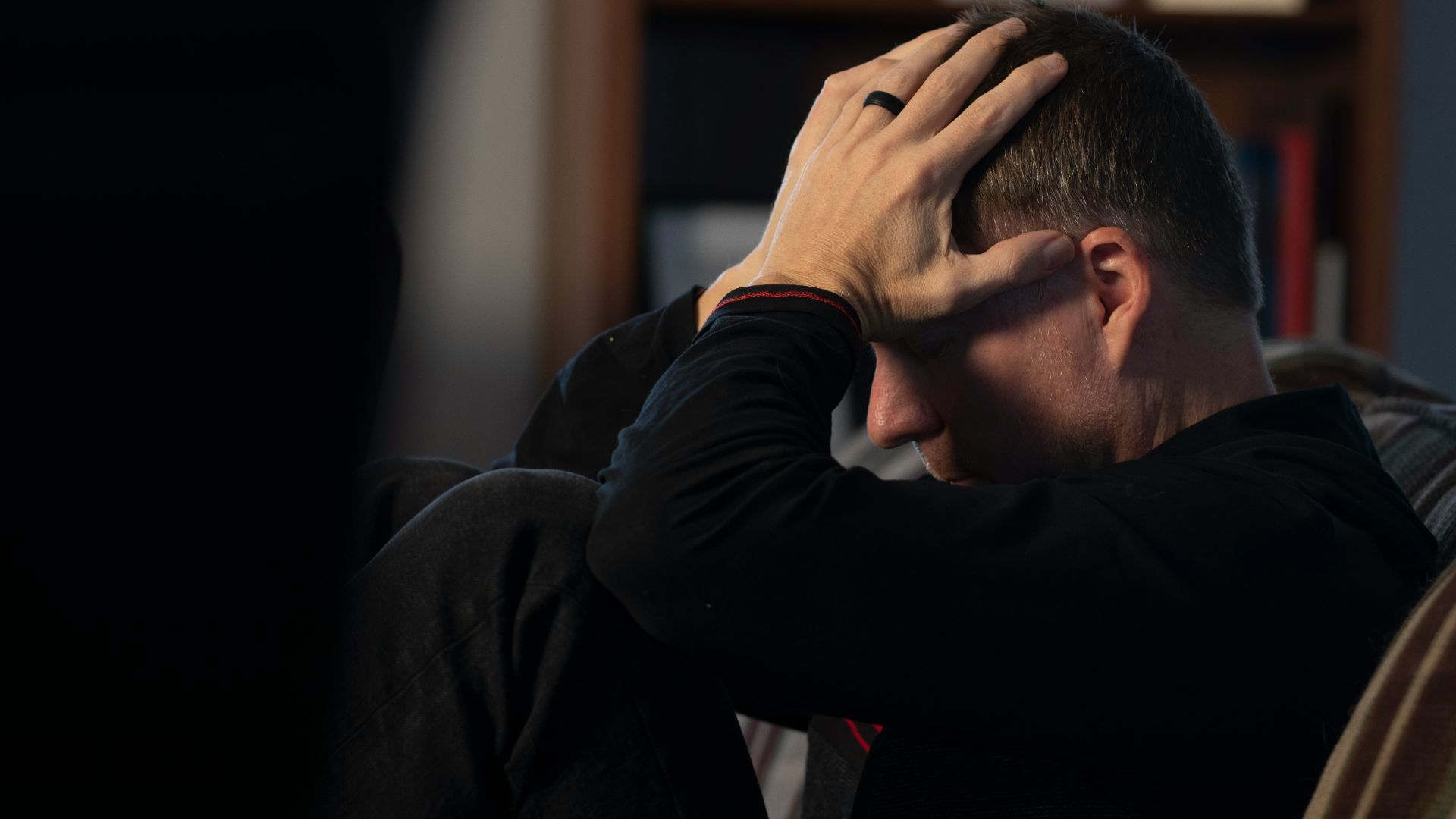 a man sitting on a couch holding his head in his hands
