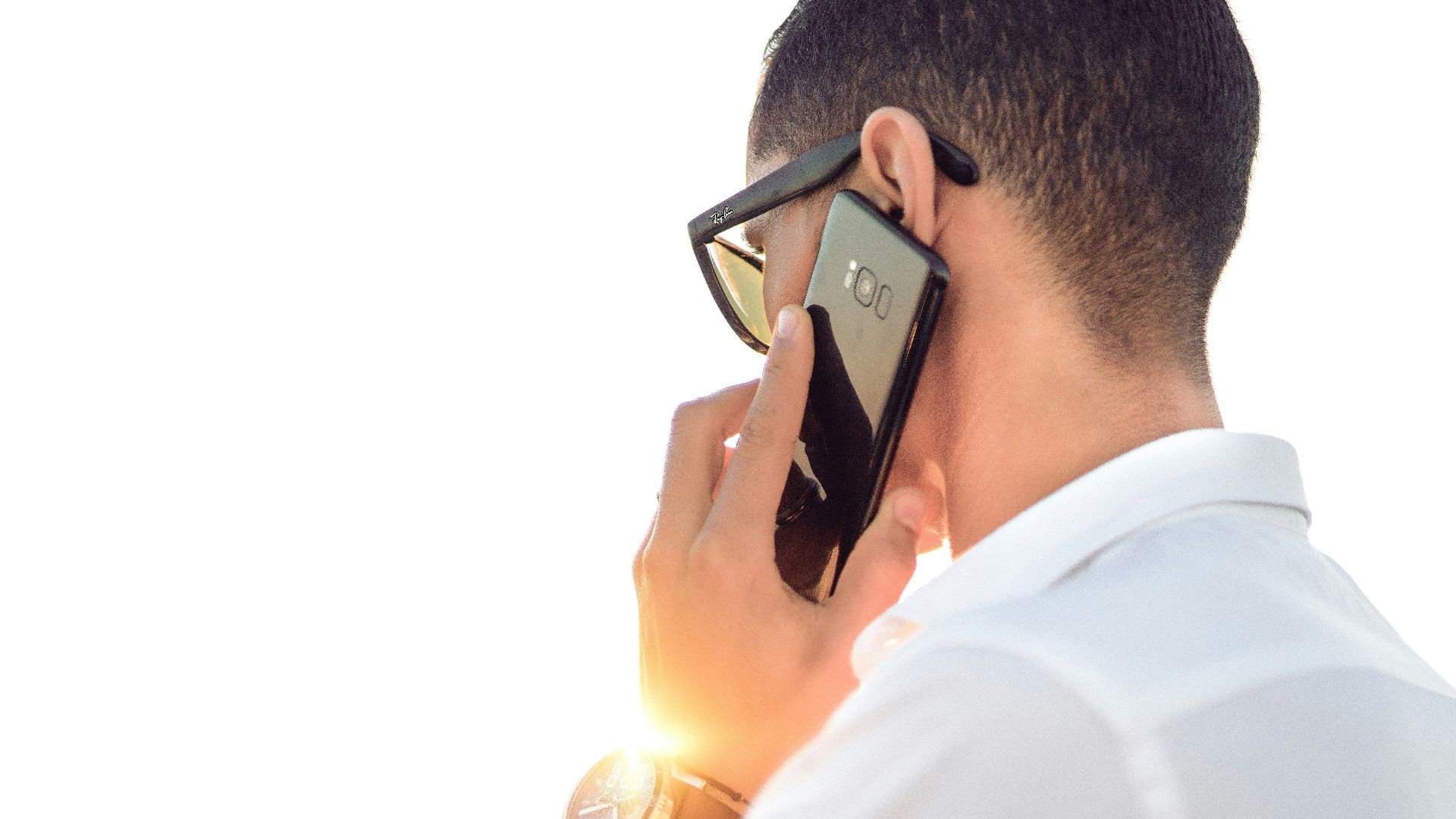 man holding smartphone standing in front of calm body of water