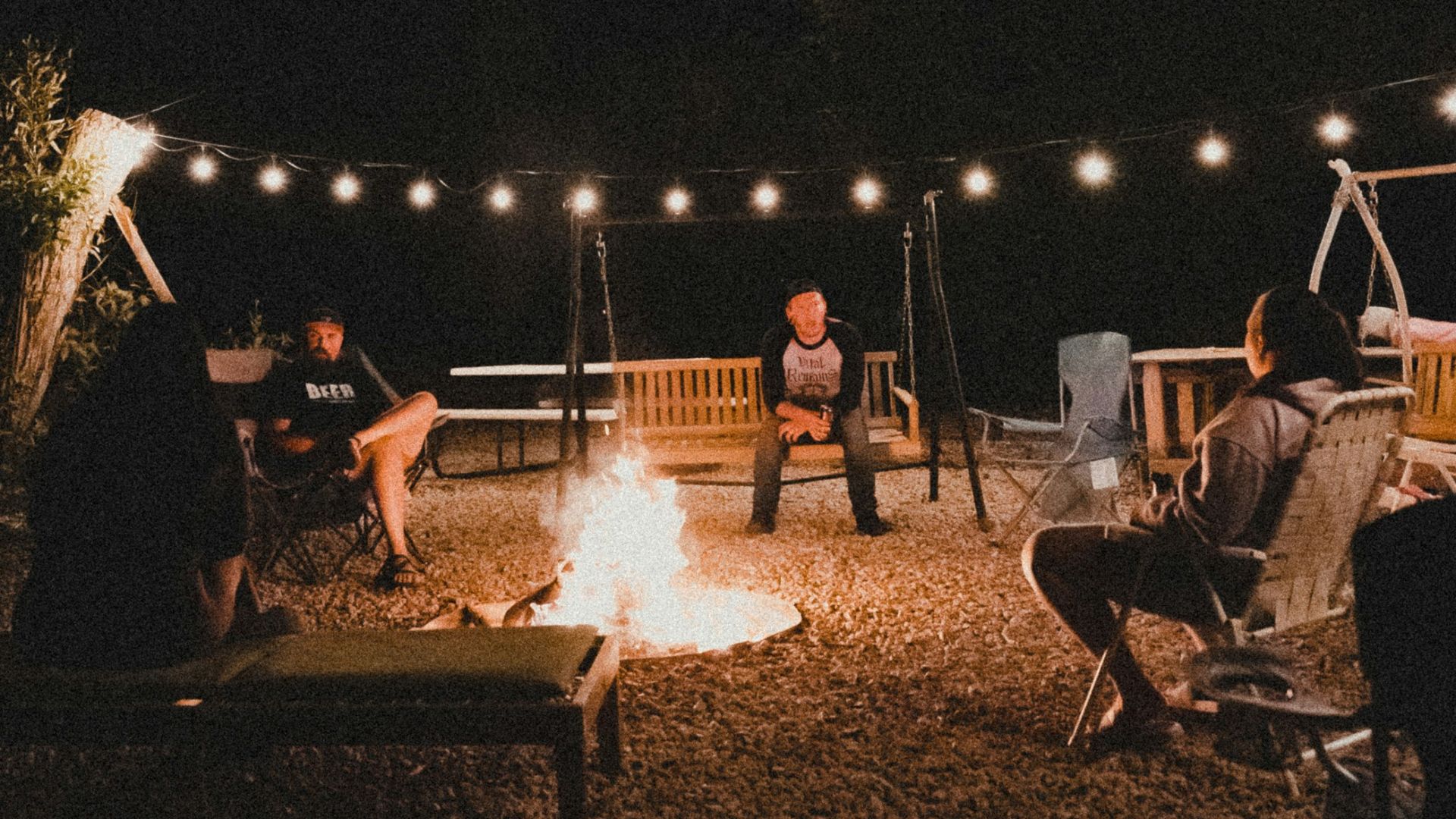 a group of people sitting around a fire at night