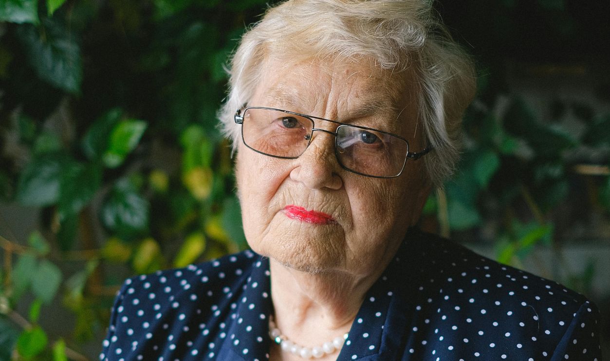 Senior woman using a tablet indoors surrounded by greenery, showcasing modern technology use