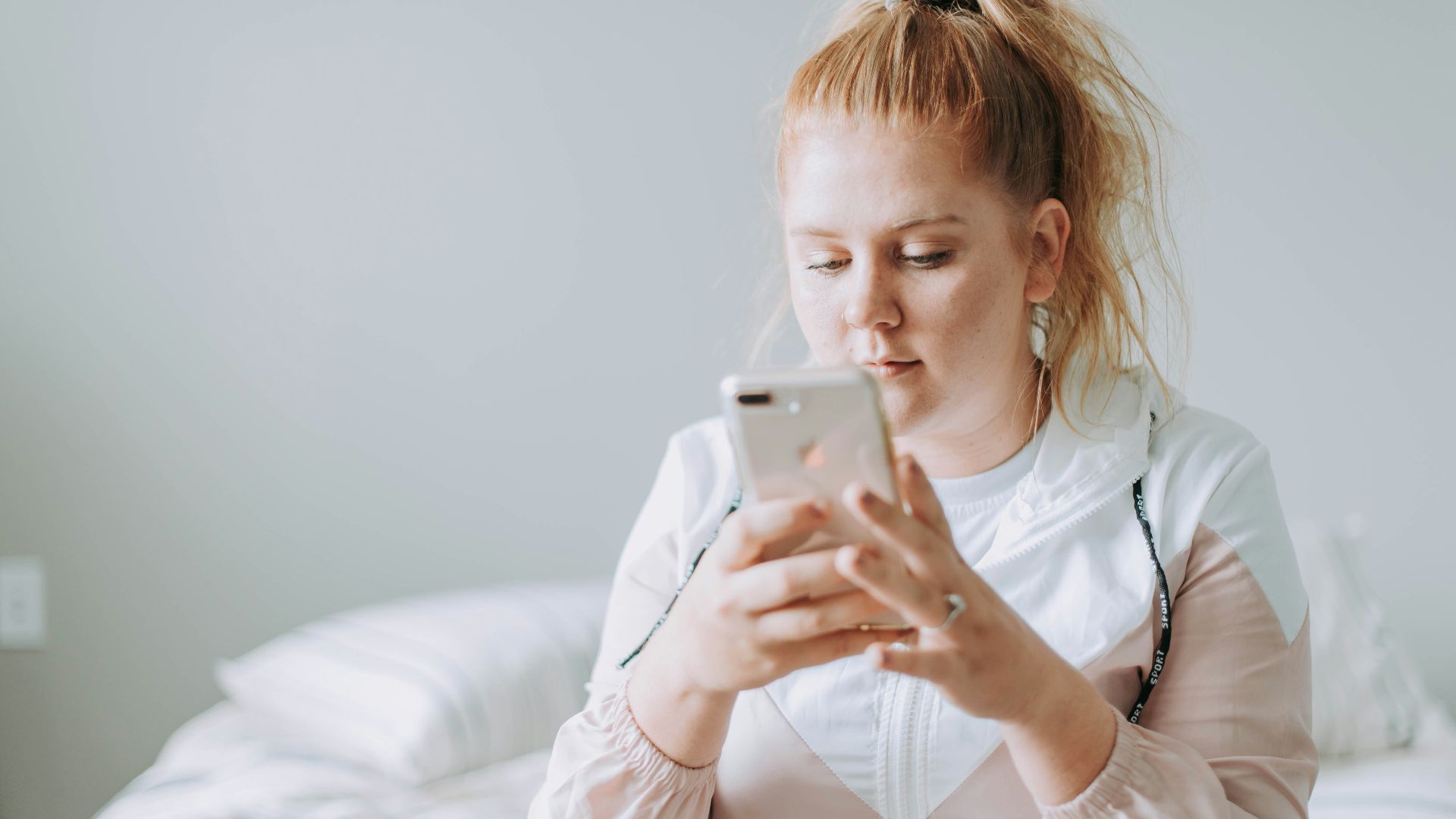 woman sitting on bed while using gold turned 8 Plus