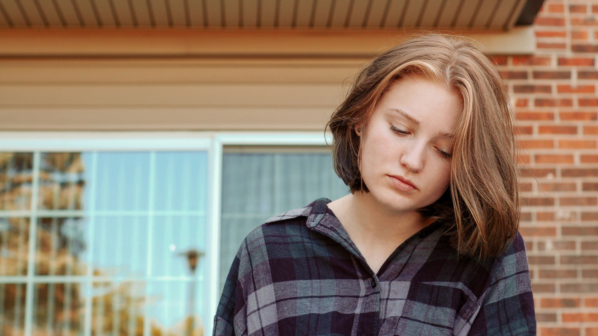 woman looks down outside red brick building