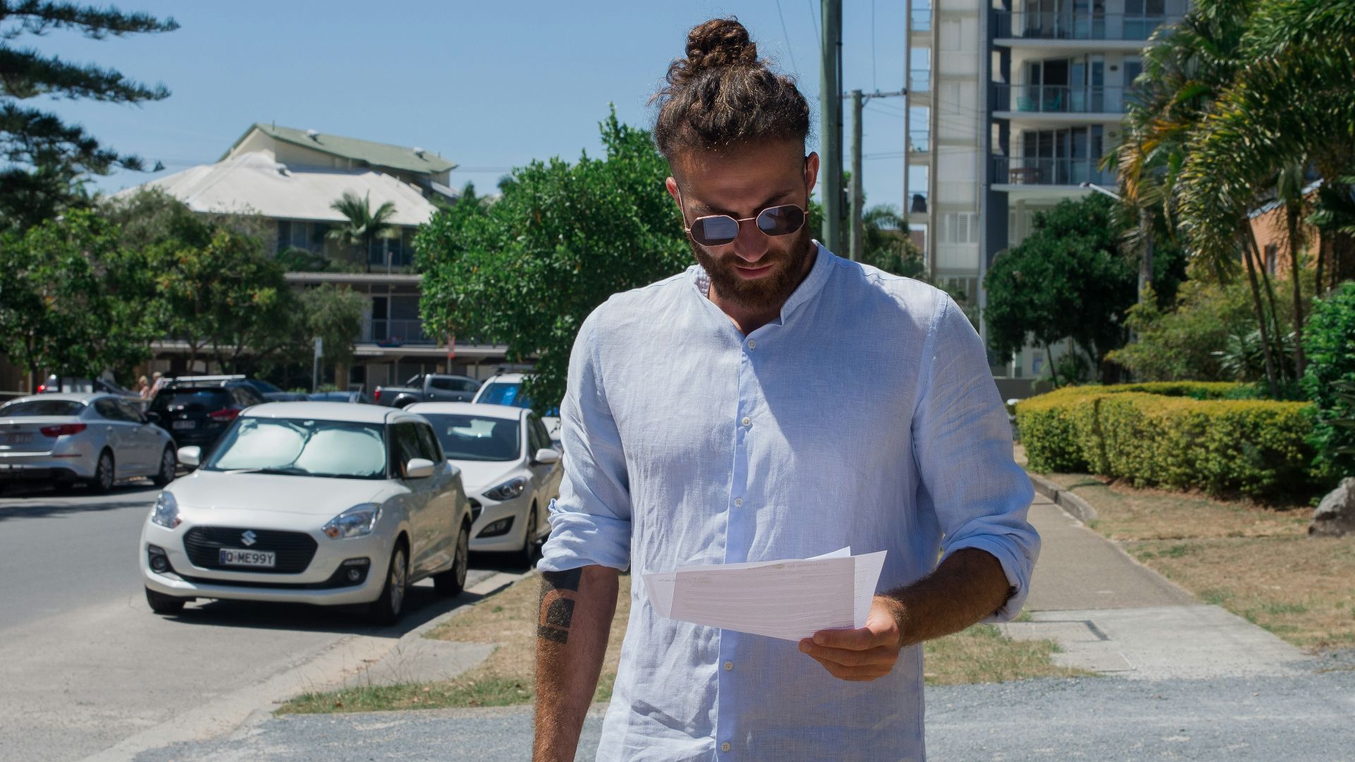 man in white button up t-shirt holding white printer paper