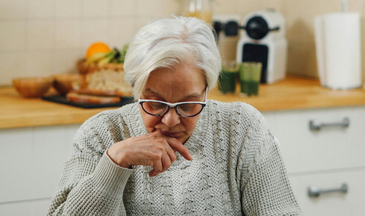 Senior woman reading at a kitchen table, deep in thought