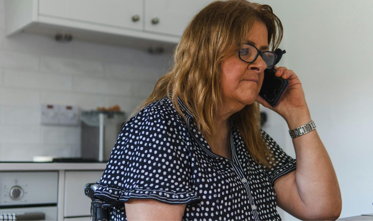 Adult woman talking on phone in a contemporary kitchen, wearing polka dot clothing