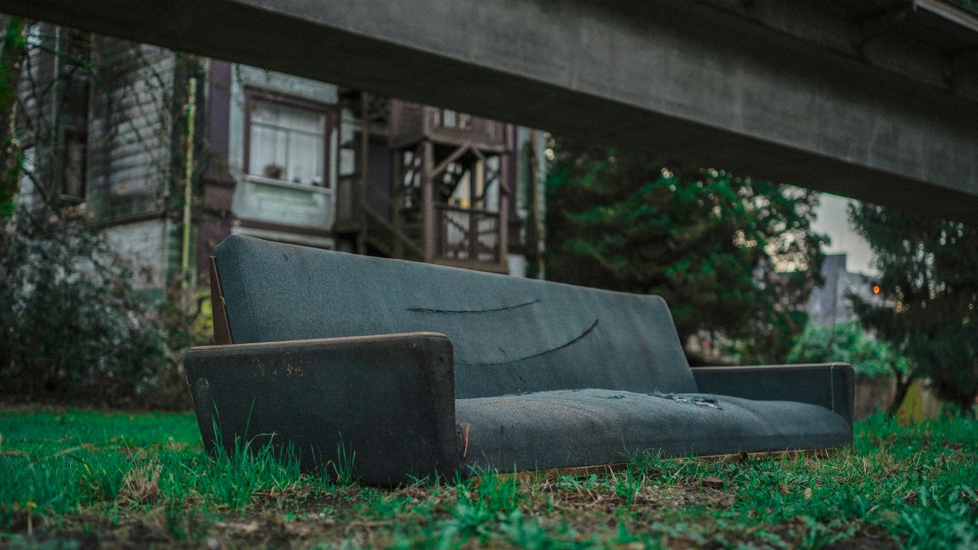 a black couch sitting on top of a lush green field